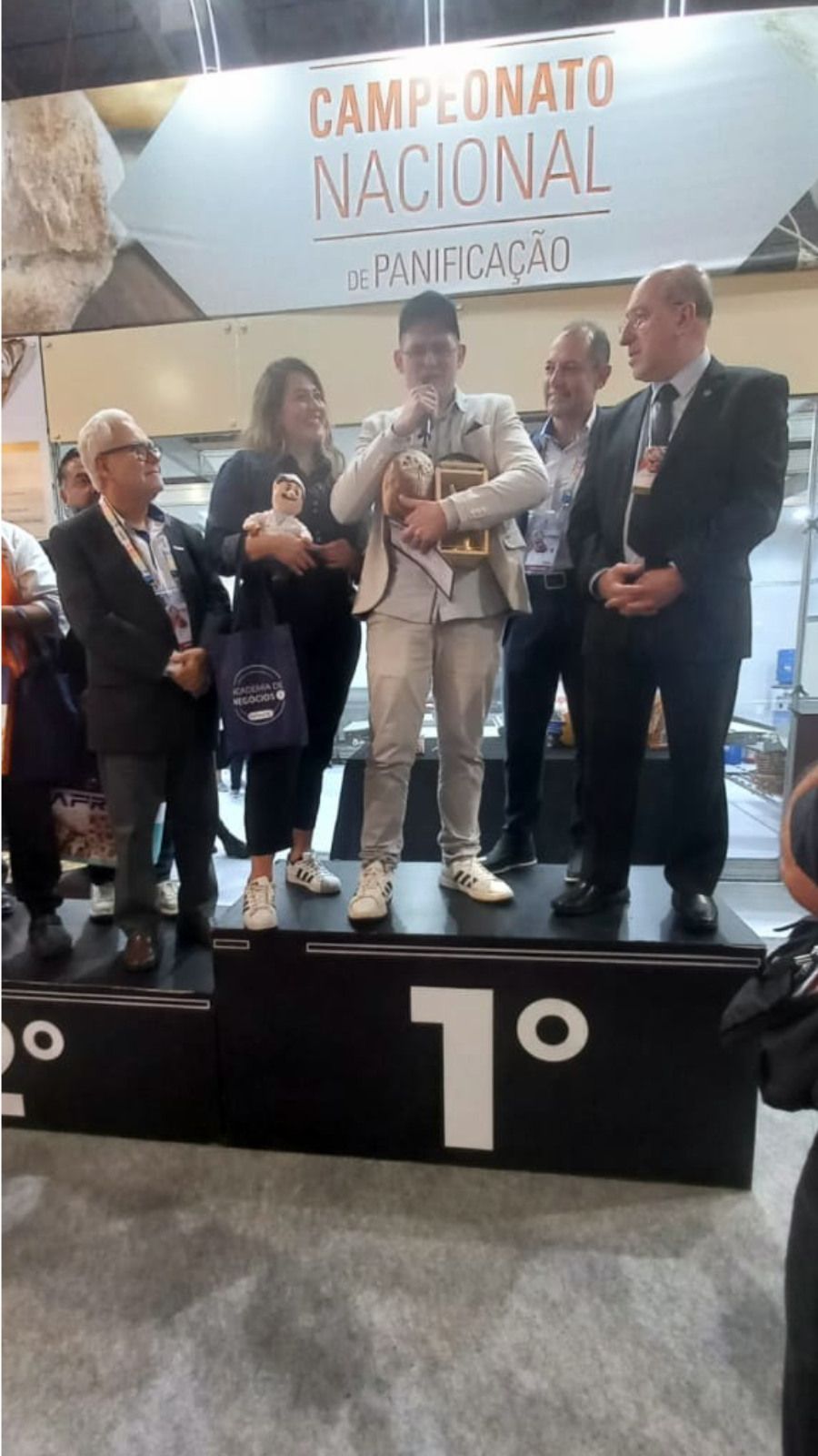 Um homem está em pé em um pódio segurando um cachorro.