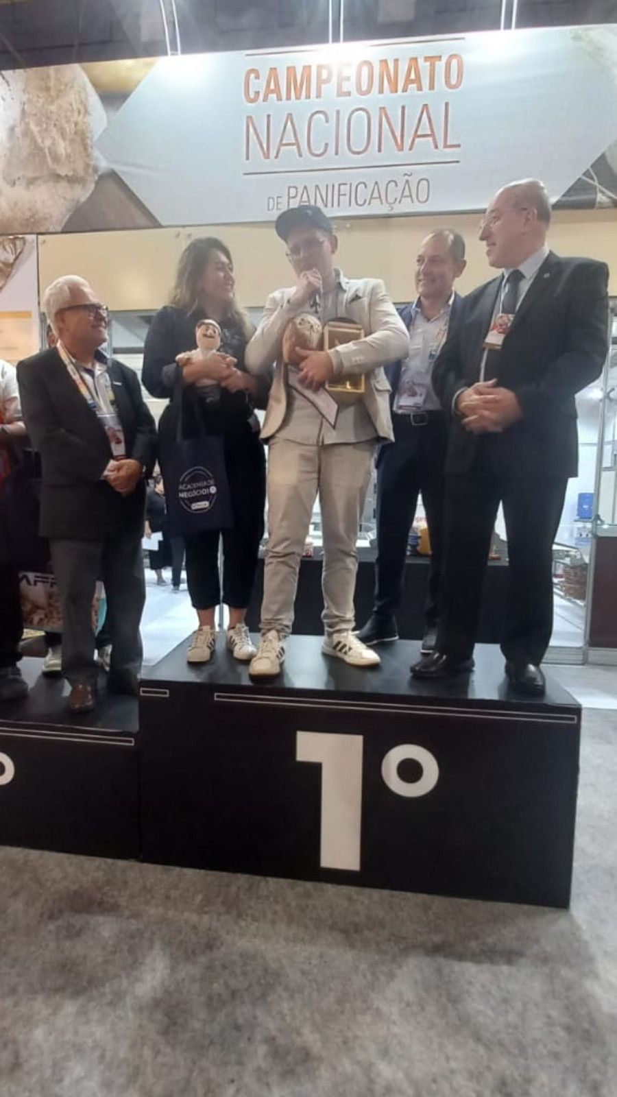 Um grupo de pessoas está em um pódio segurando troféus.