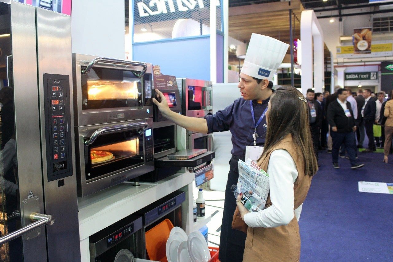 Um homem e uma mulher estão olhando para um forno em uma convenção.