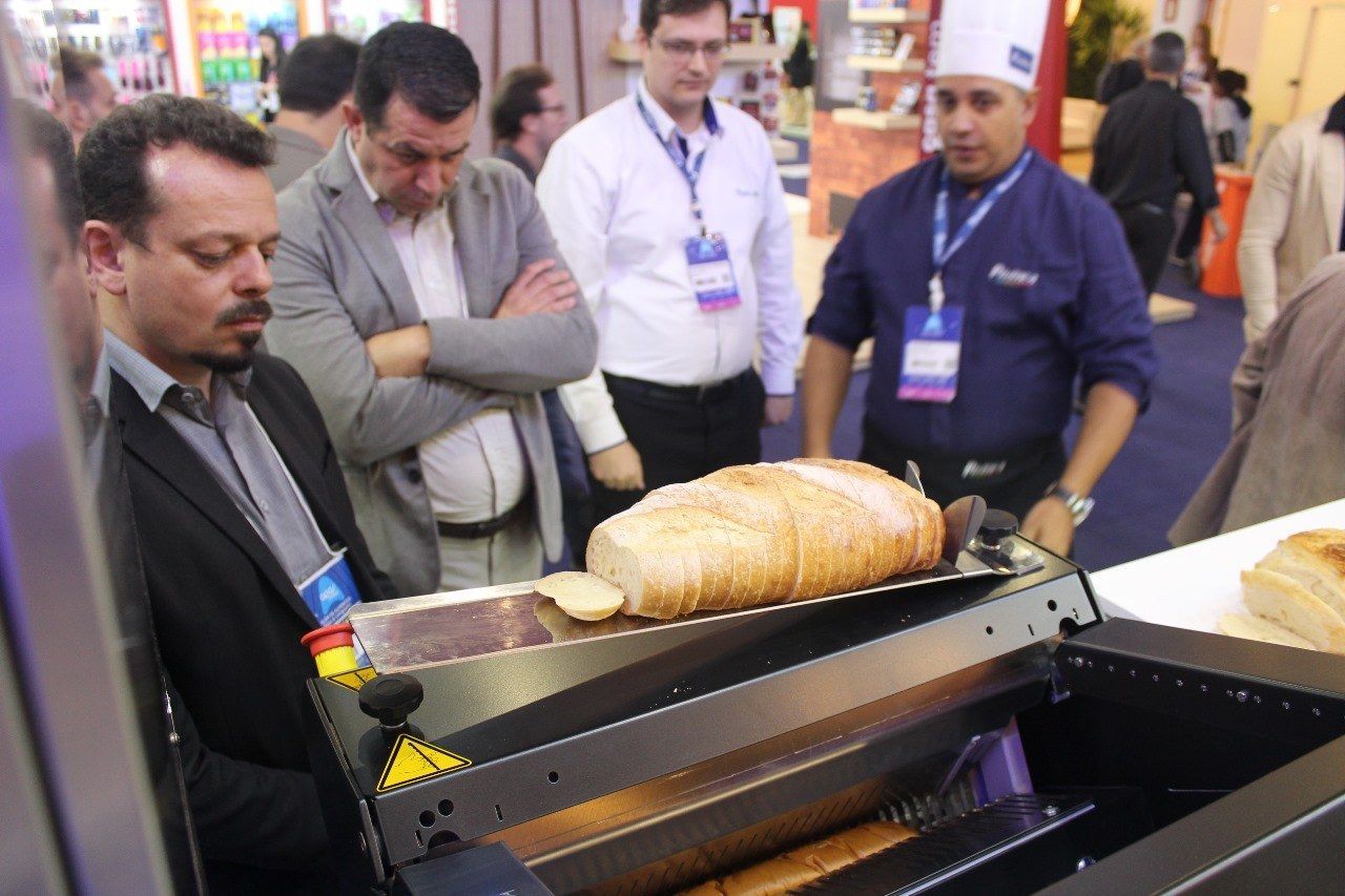 Um grupo de homens está olhando para uma máquina que está fazendo pão