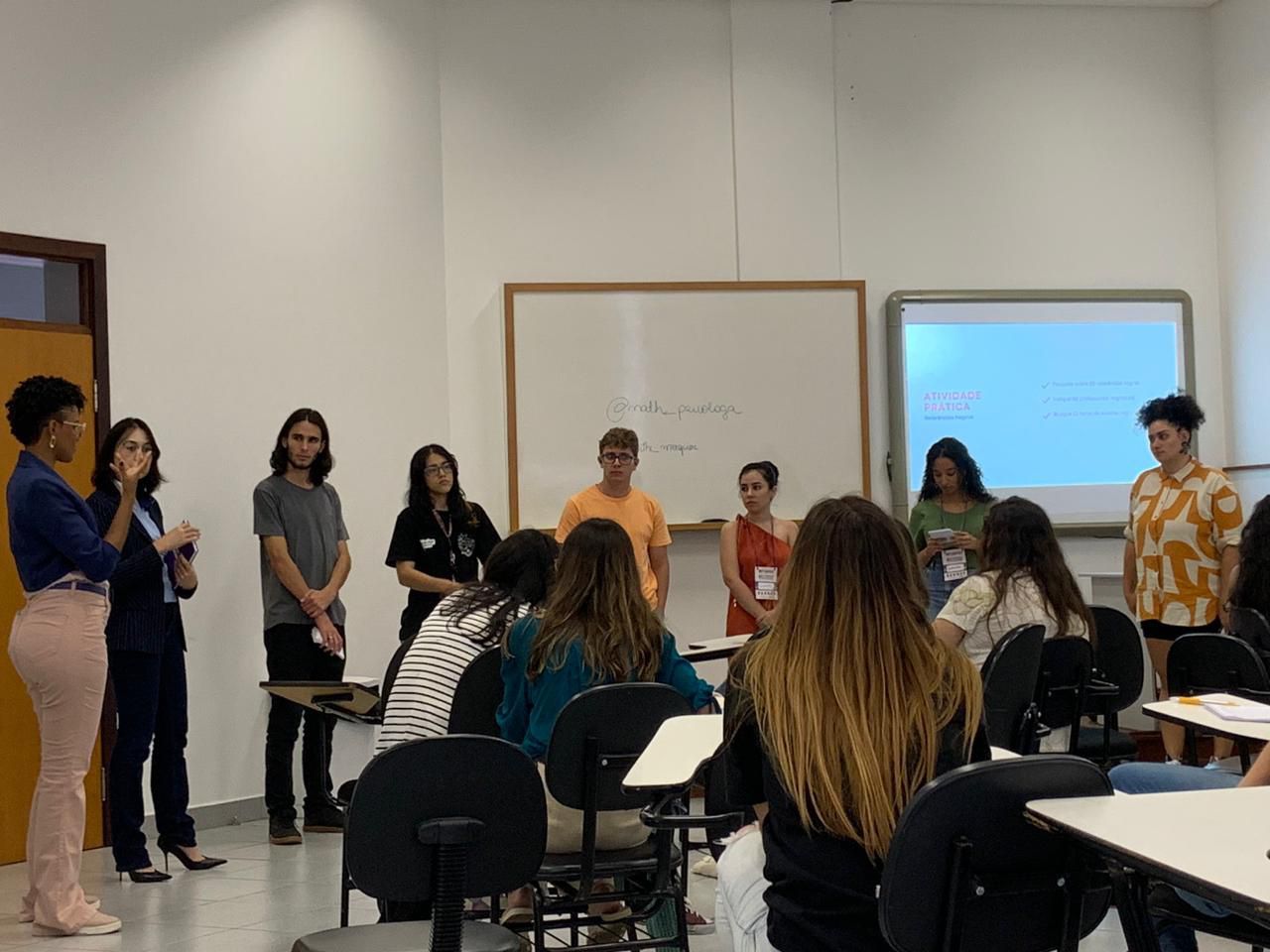 Um grupo de pessoas está em uma sala de aula conversando entre si.