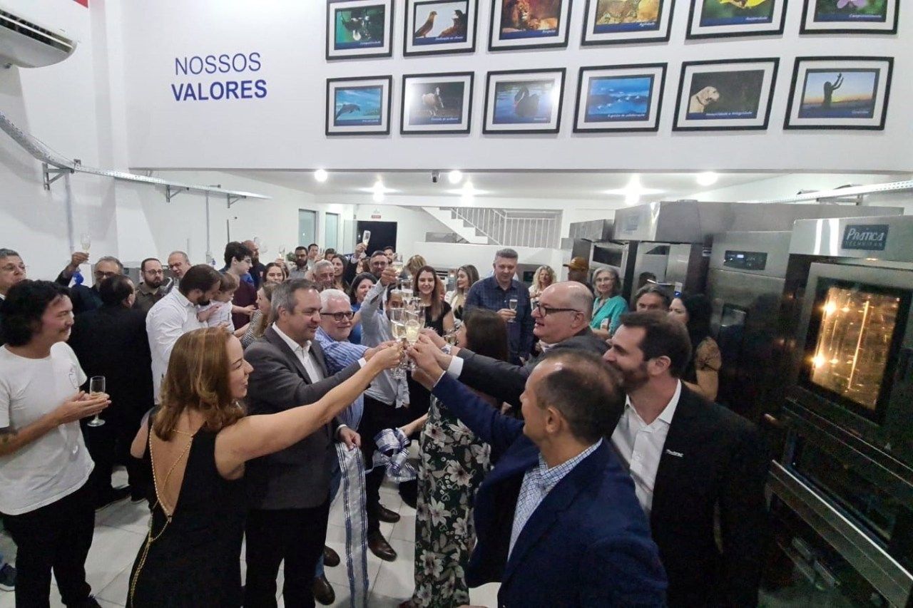 Um grupo de pessoas brinda em frente a uma placa que diz nossos valores