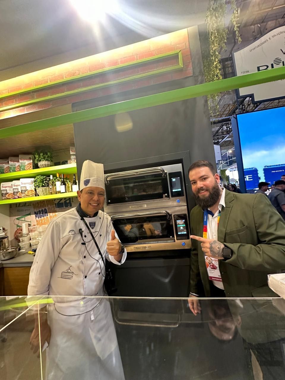 Dois homens estão de pé, um ao lado do outro, em frente a um forno de micro-ondas.