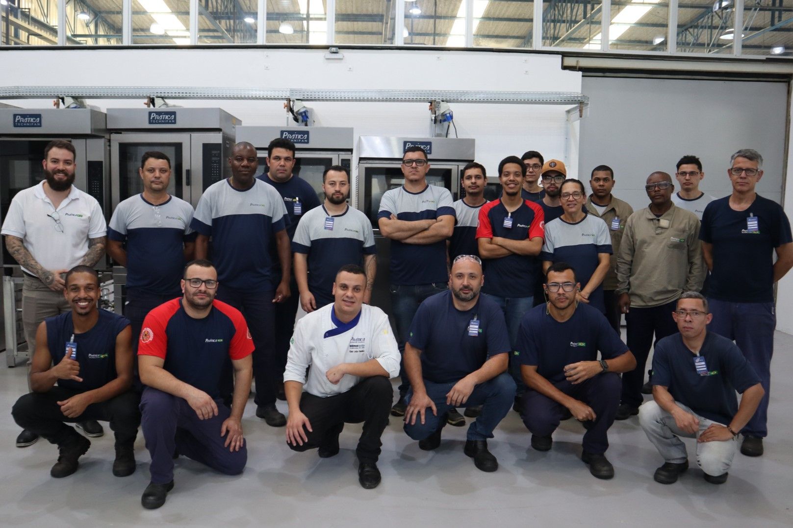 Um grupo de homens está posando para uma foto em uma fábrica.