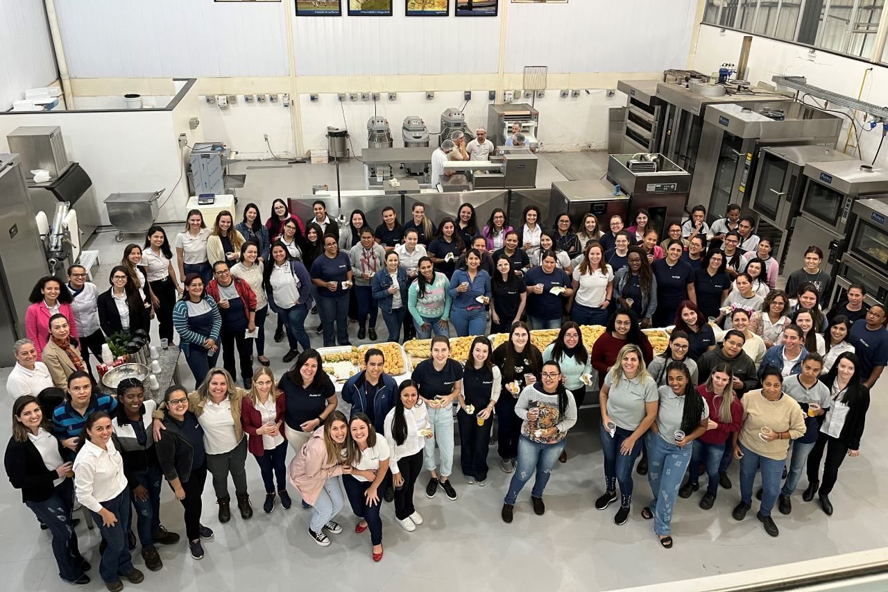 Um grande grupo de pessoas está posando para uma foto em uma cozinha.