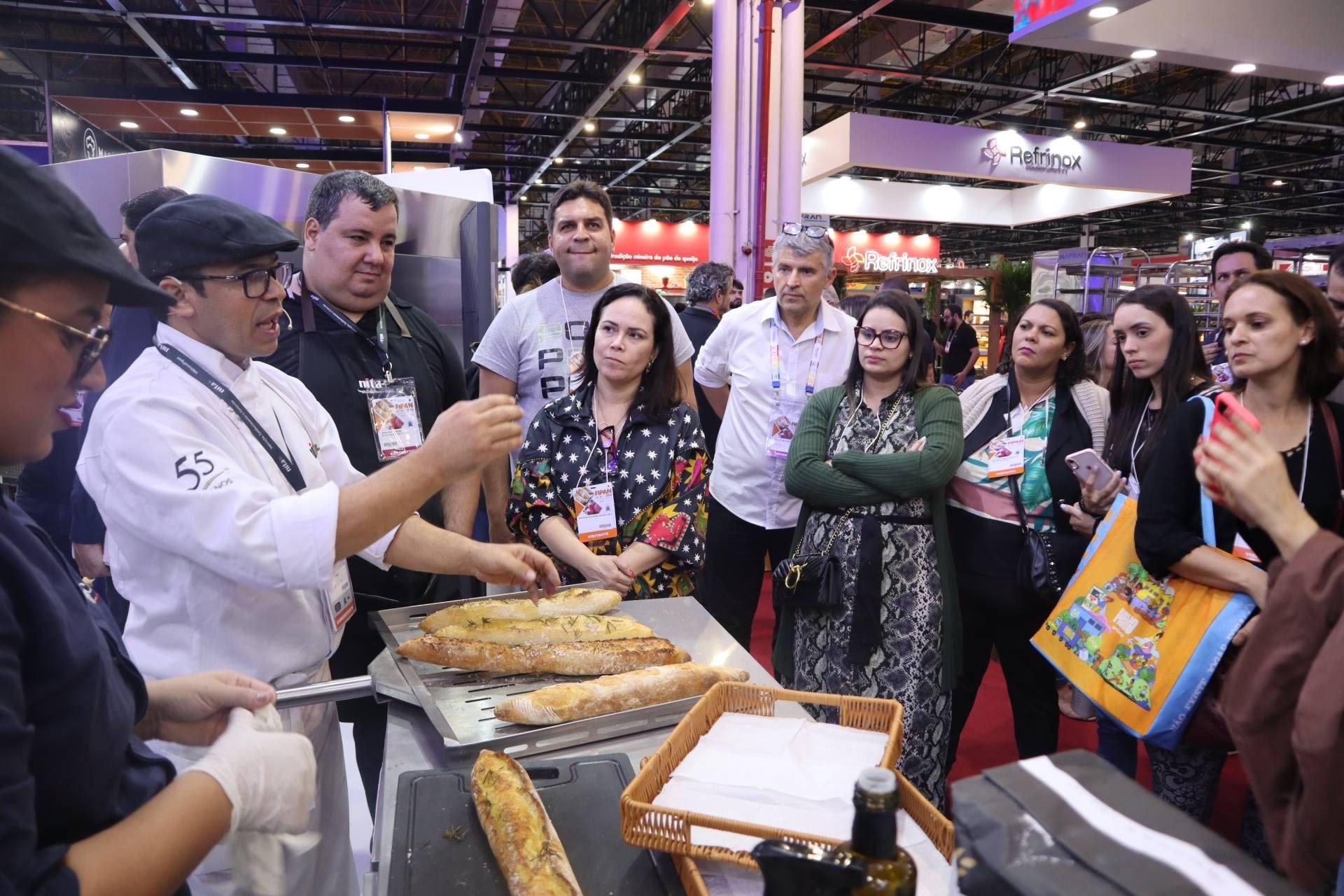Um grupo de pessoas está em pé ao redor de uma mesa com comida.