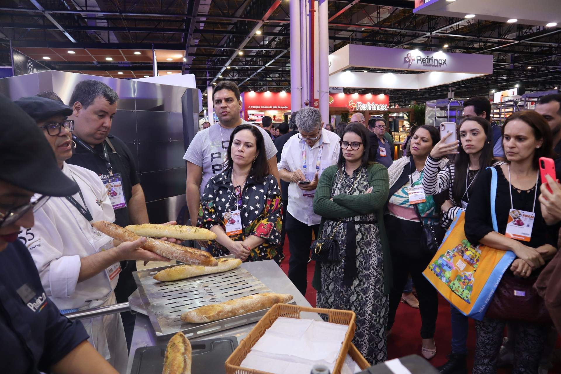 Um grupo de pessoas está de pé ao redor de uma mesa com pão sobre ela.