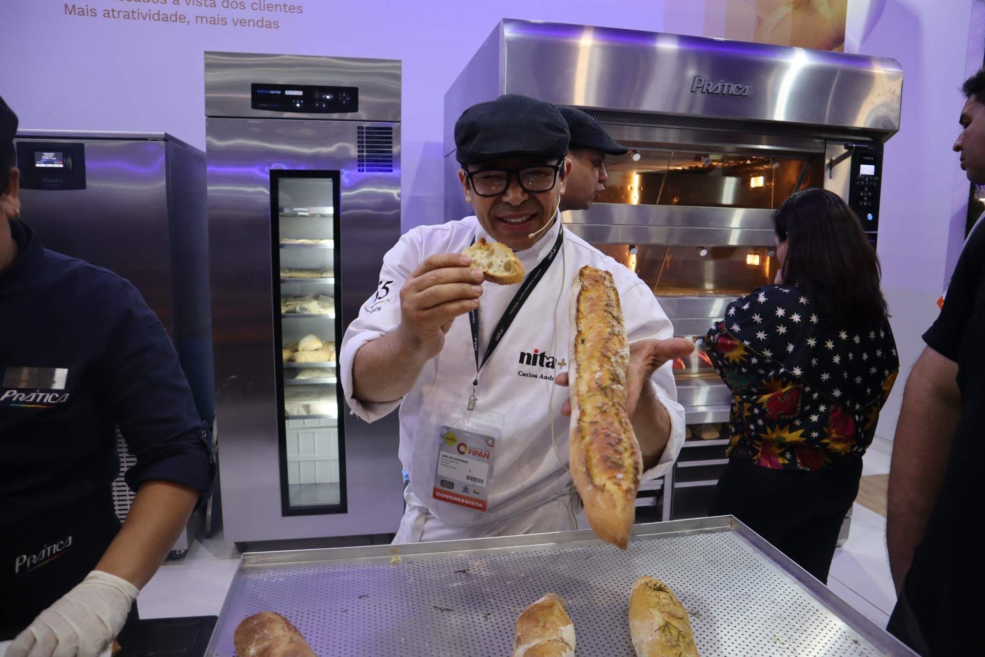 Um homem está segurando um pão em frente ao forno.