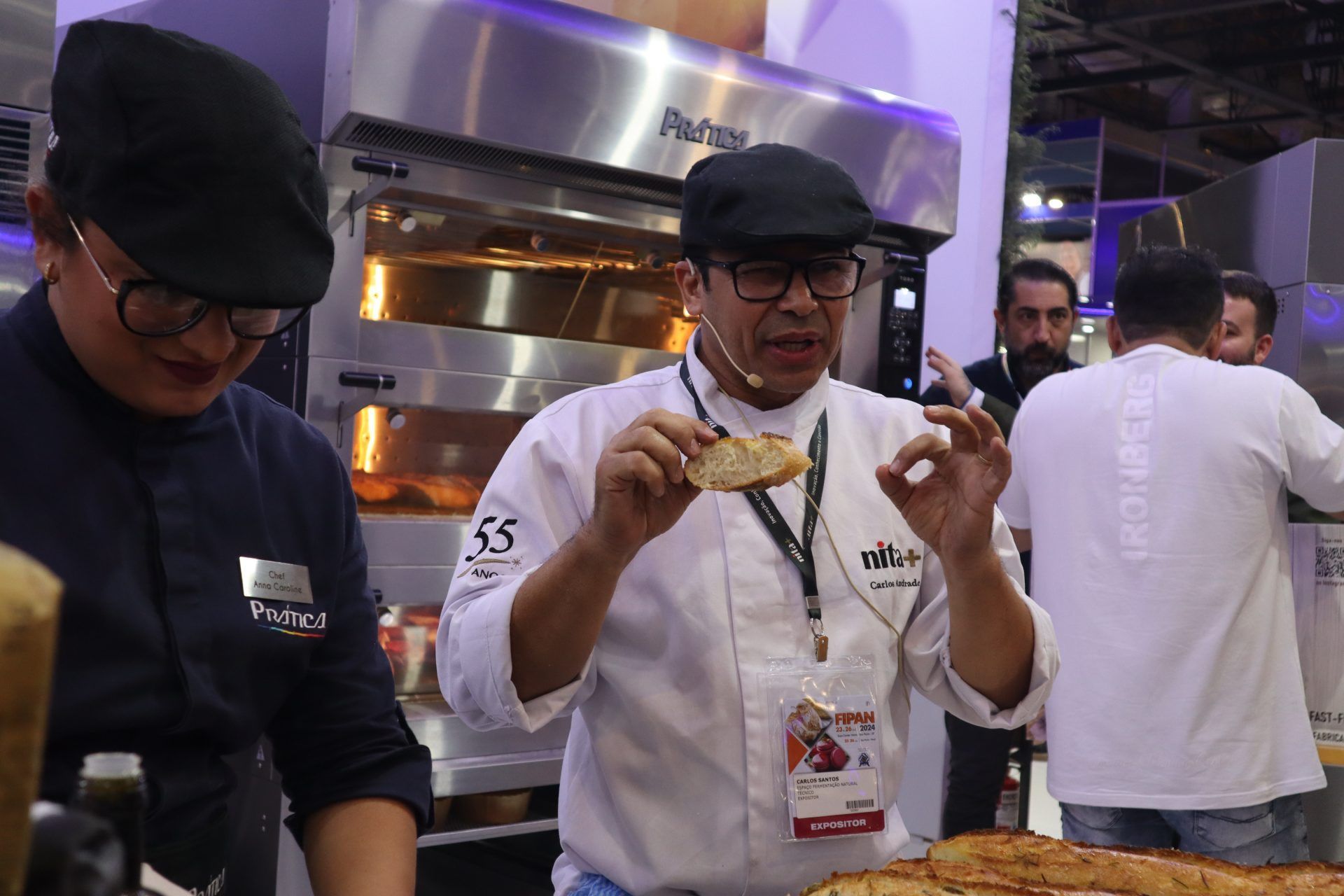 Um homem está segurando um pedaço de pão em frente ao forno.