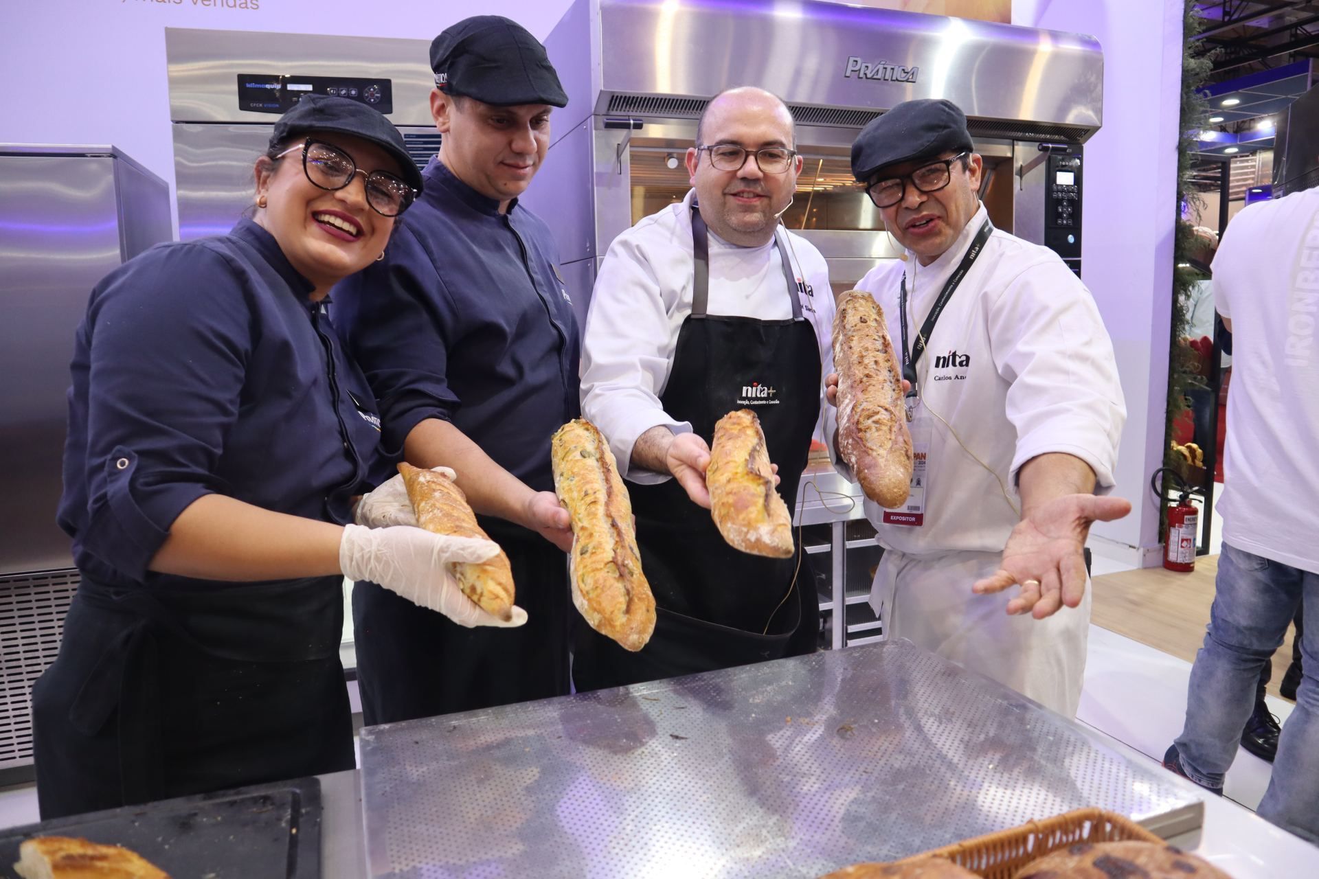 Um grupo de pessoas está de pé ao redor de uma mesa segurando pão.