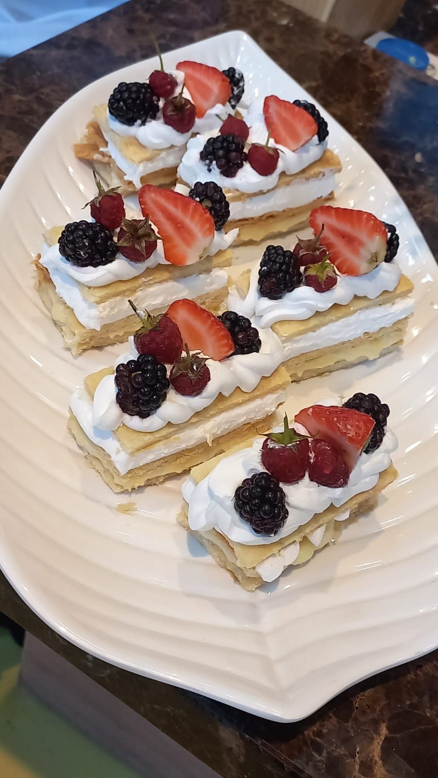 Um prato de sobremesas com chantilly e frutas vermelhas sobre uma mesa.