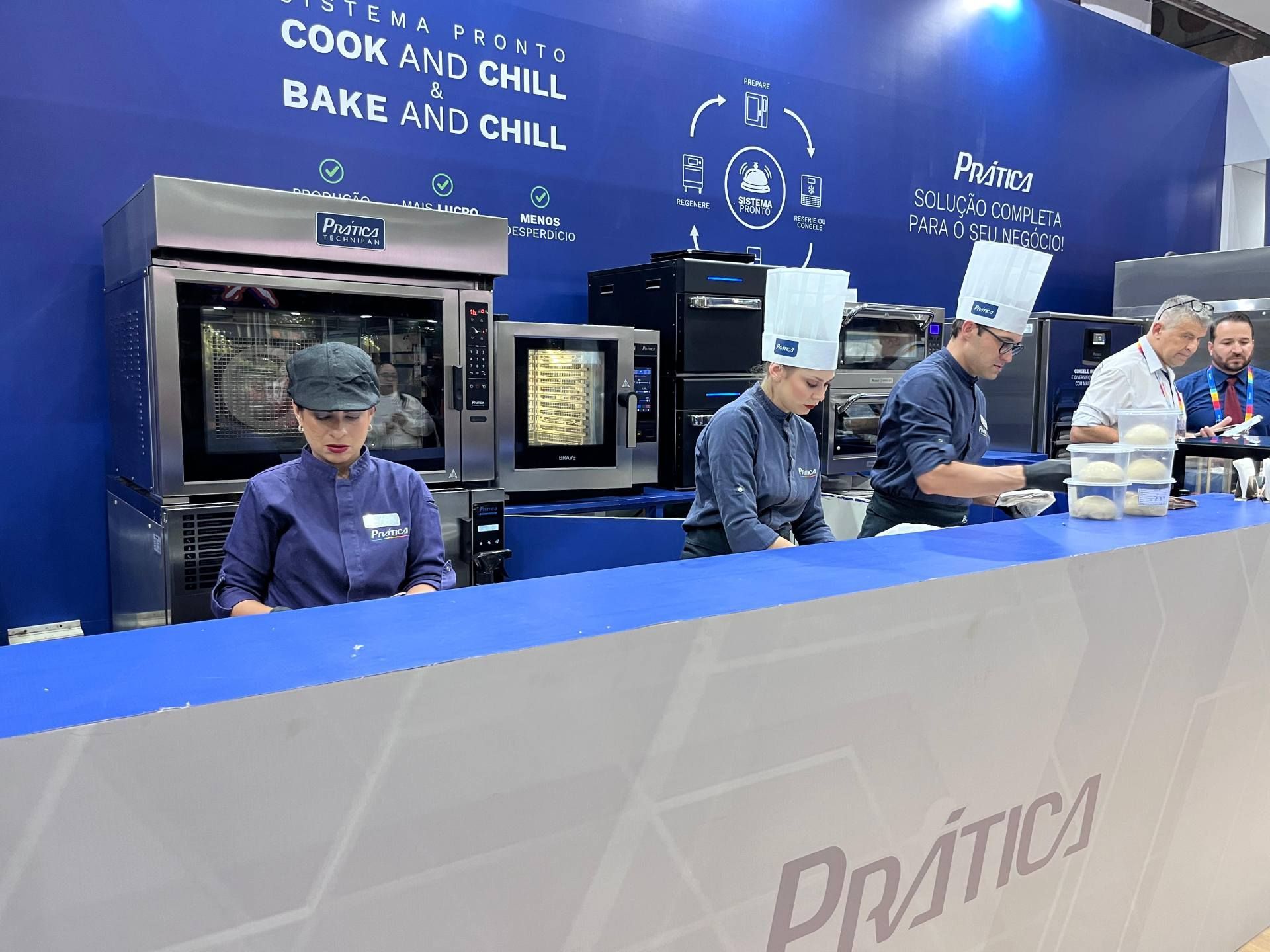 Um grupo de chefs está trabalhando em um balcão de uma cozinha.