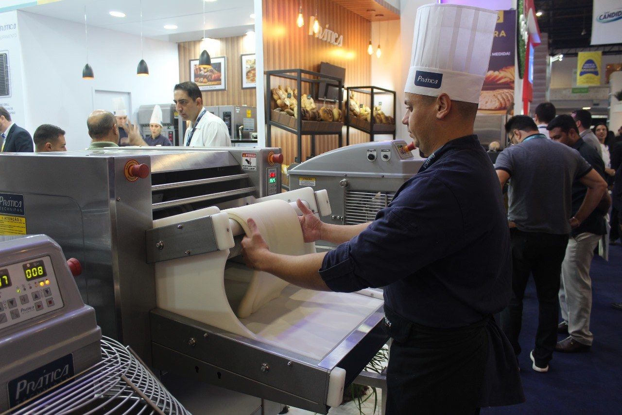 Um homem com chapéu de chef está trabalhando em uma máquina.