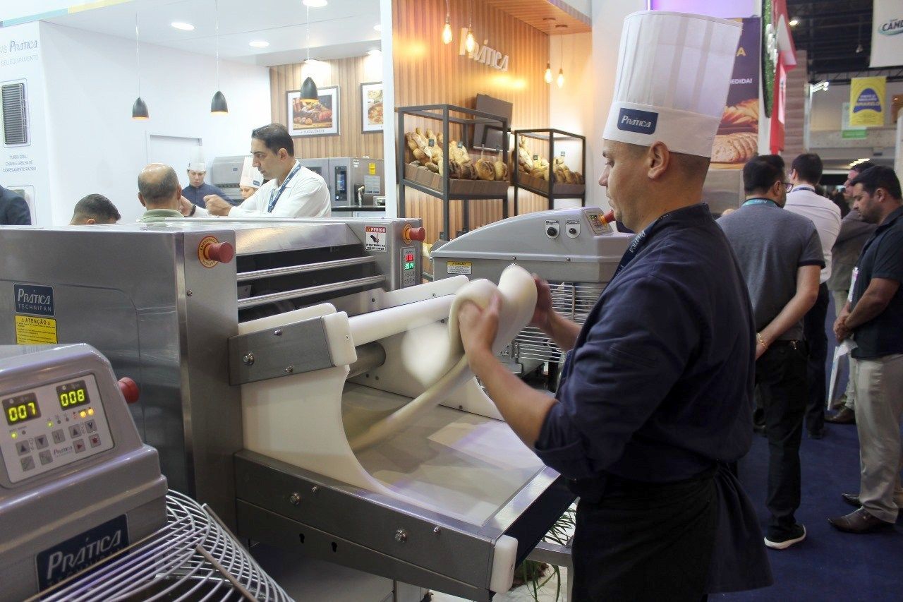 Um homem com chapéu de chef está trabalhando em uma máquina.