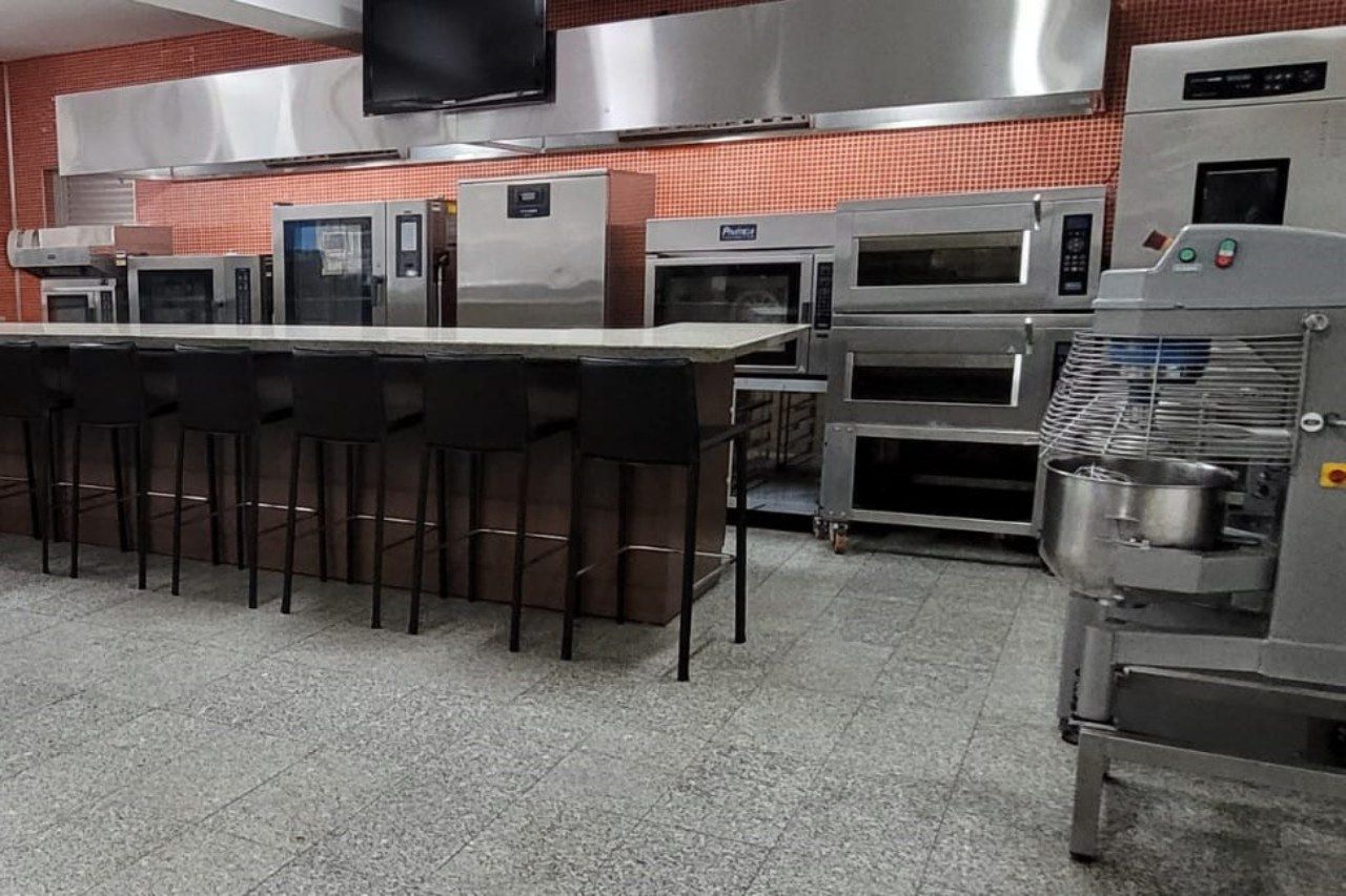 Uma cozinha com muitos eletrodomésticos de aço inoxidável e um balcão longo.