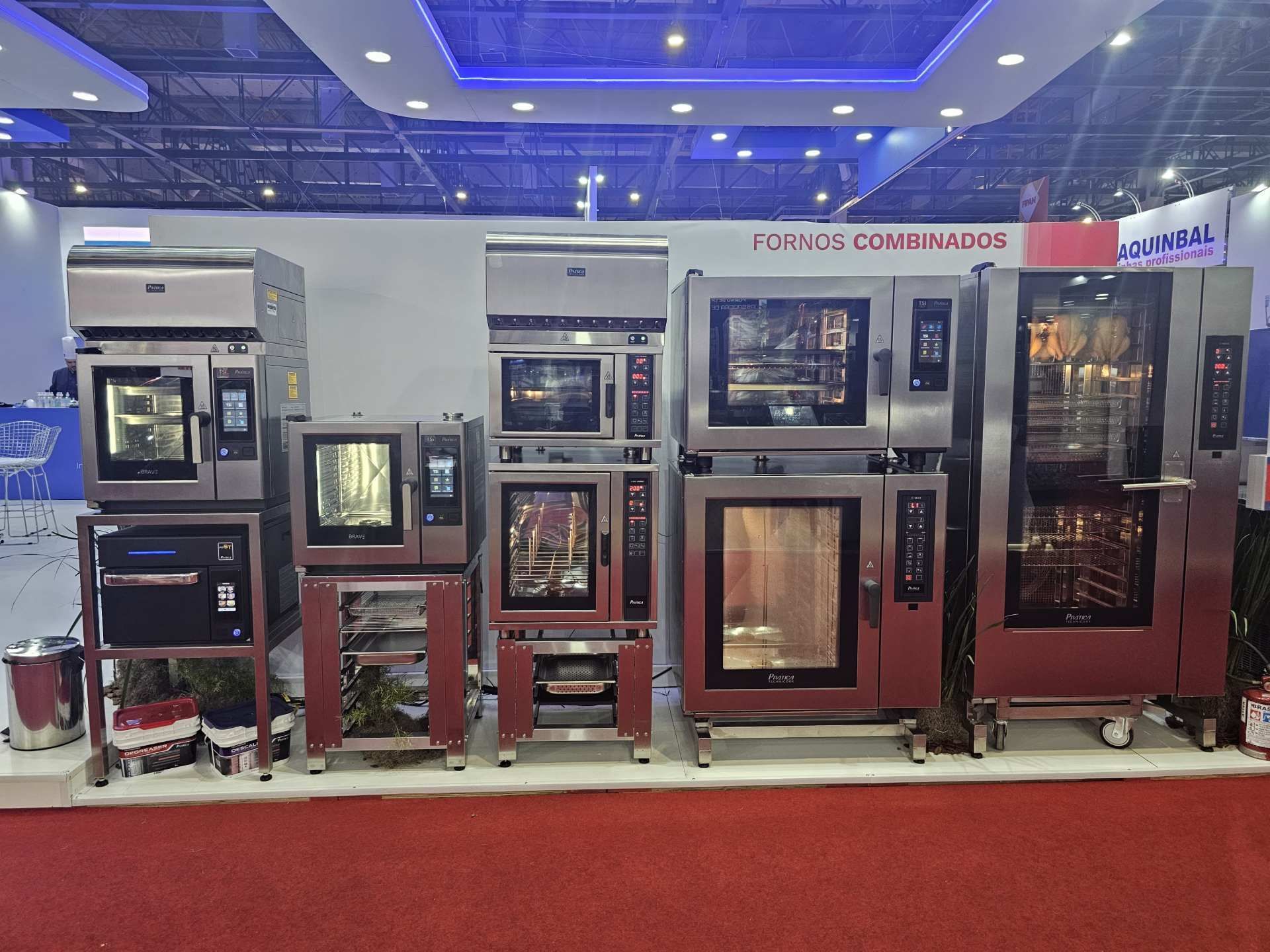 Uma fileira de fornos comerciais estão alinhados em uma sala.