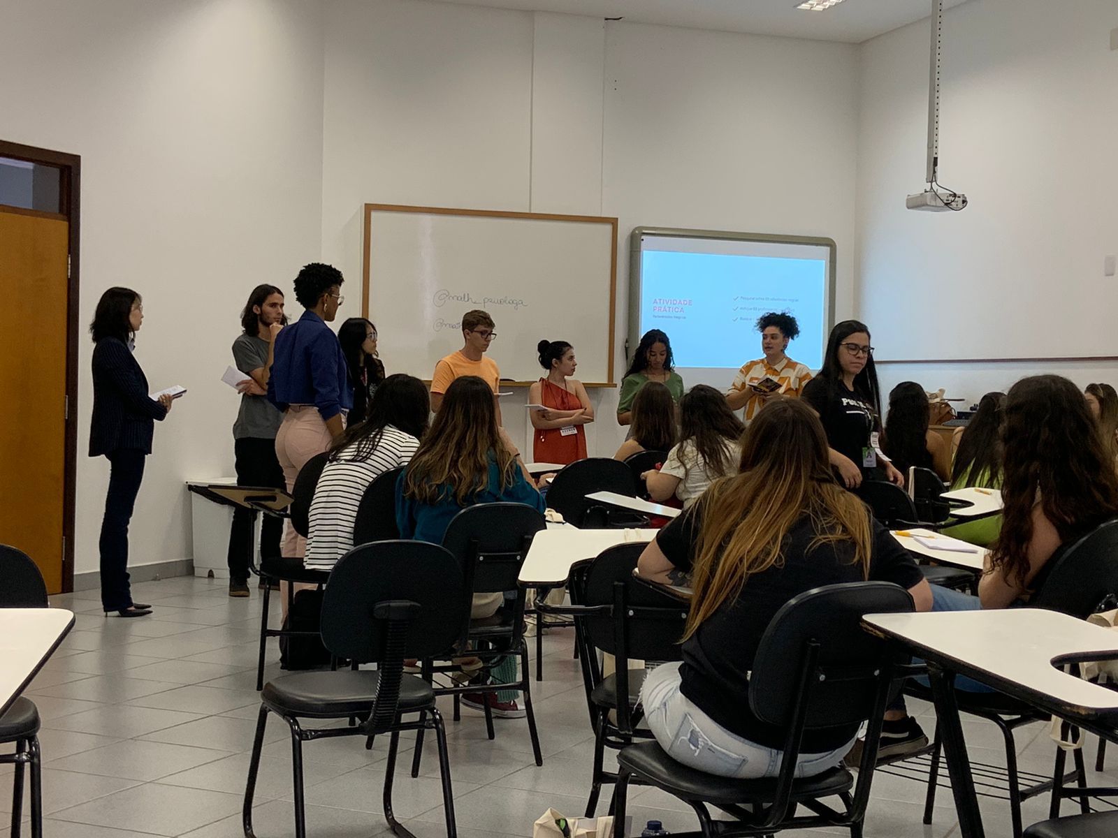 Um grupo de pessoas está sentado em carteiras em uma sala de aula.