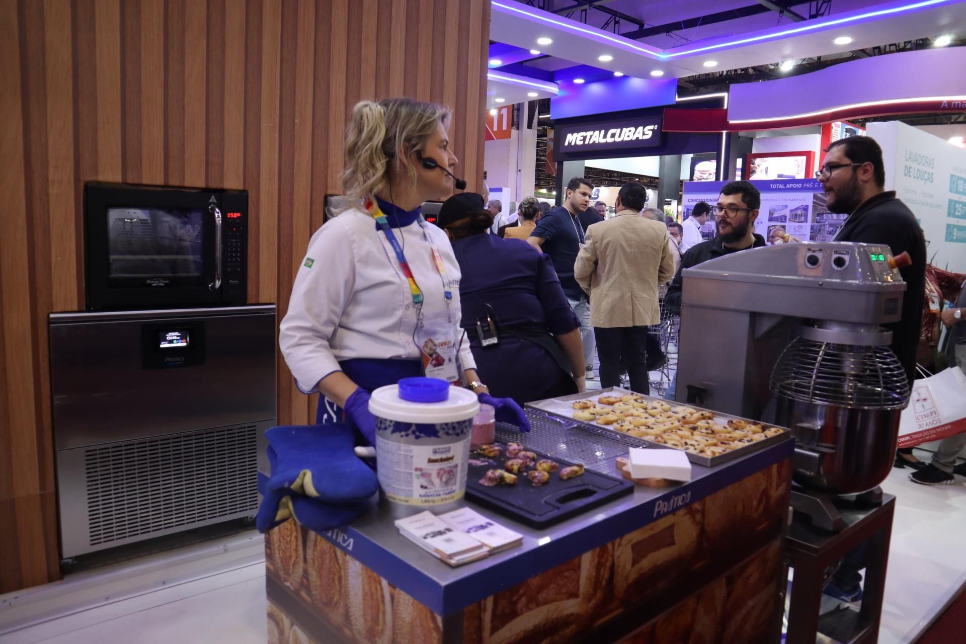 Uma mulher está parada em frente a uma mesa com comida.