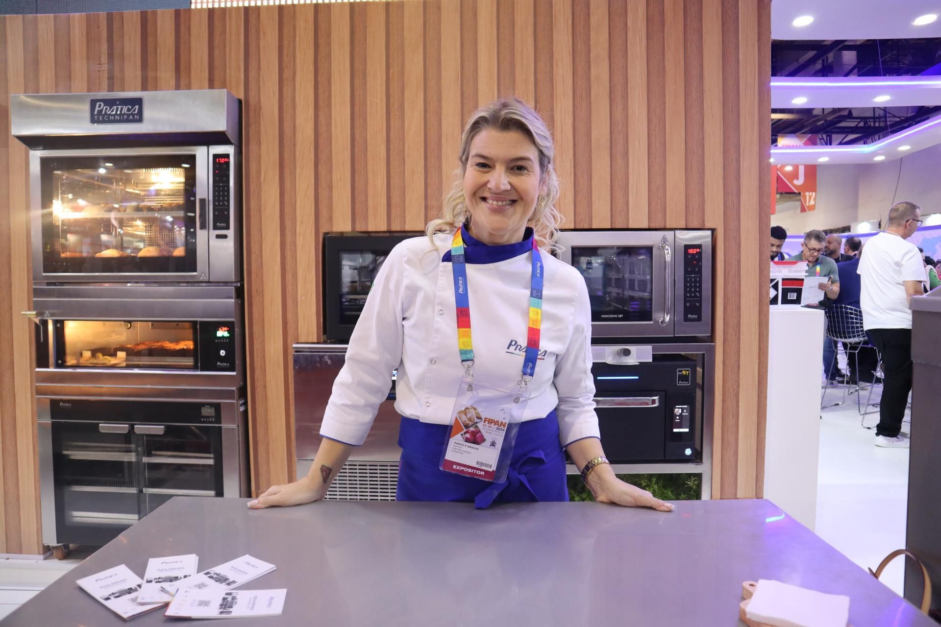 Uma mulher está parada em frente a uma mesa na cozinha.