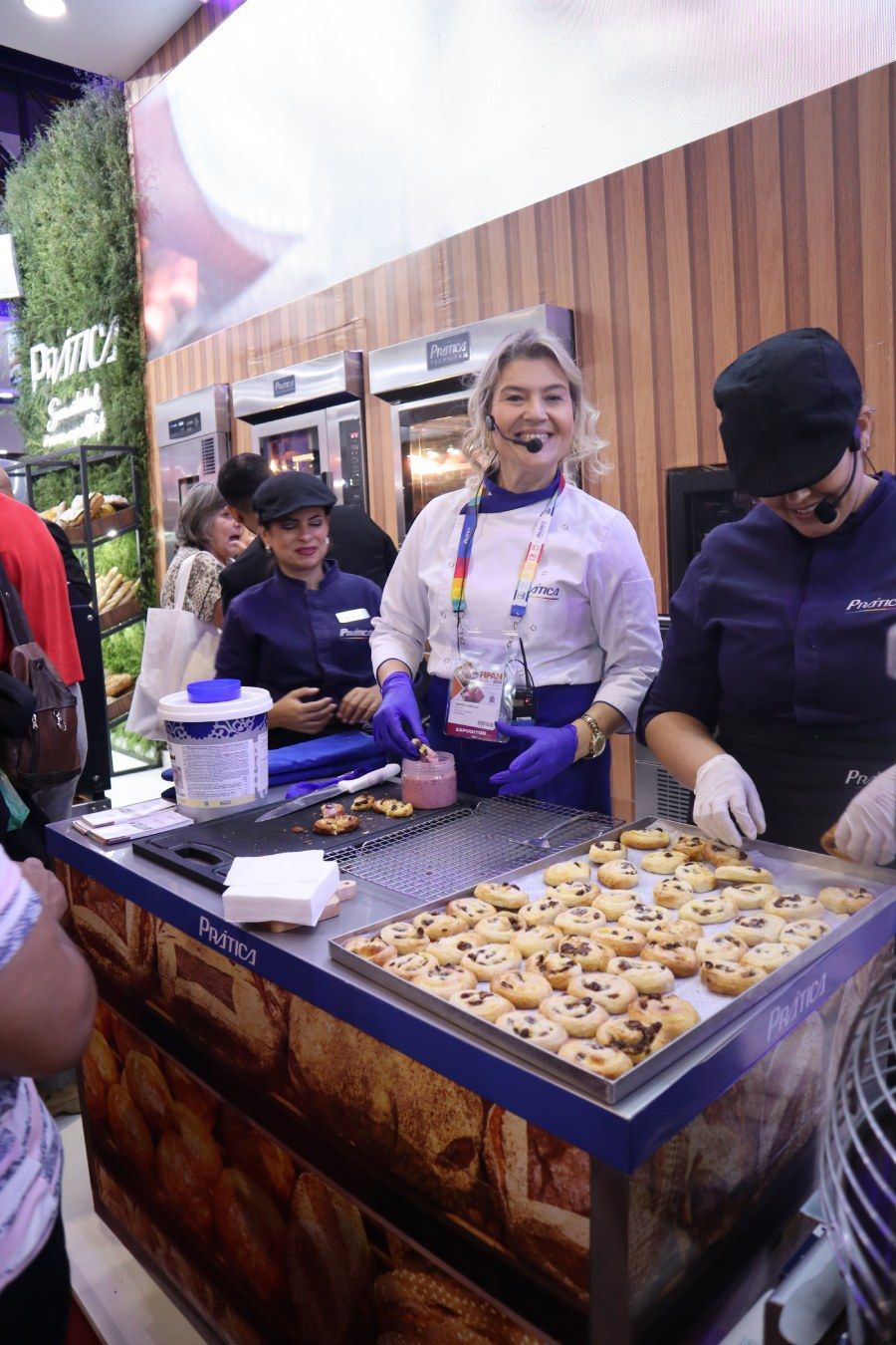 Um grupo de pessoas está em pé ao redor de uma mesa com biscoitos sobre ela.