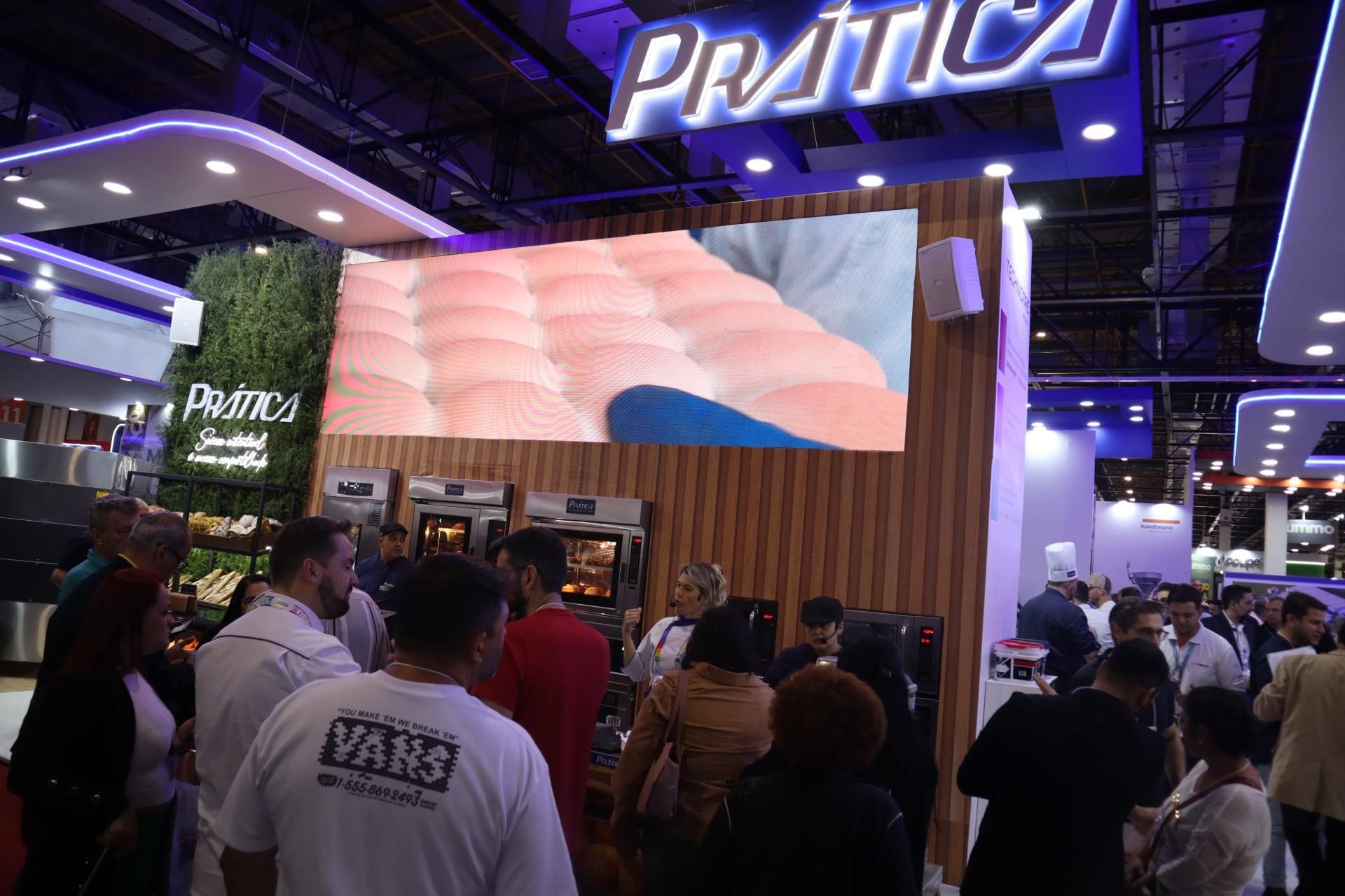 Um grupo de pessoas está em pé em frente a uma tela grande.