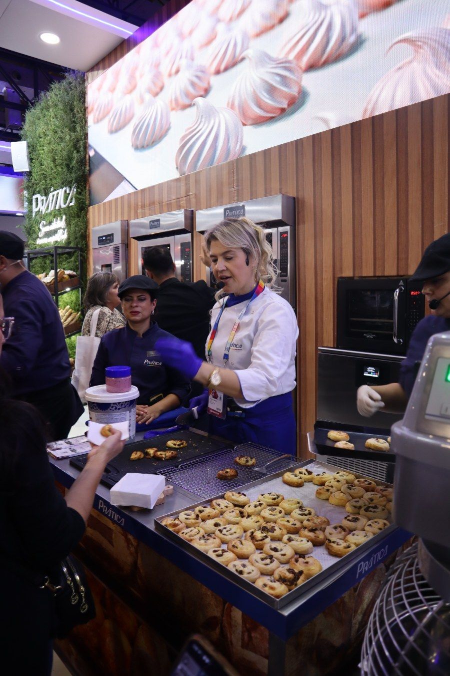 Uma mulher está parada em frente a uma mesa cheia de biscoitos.