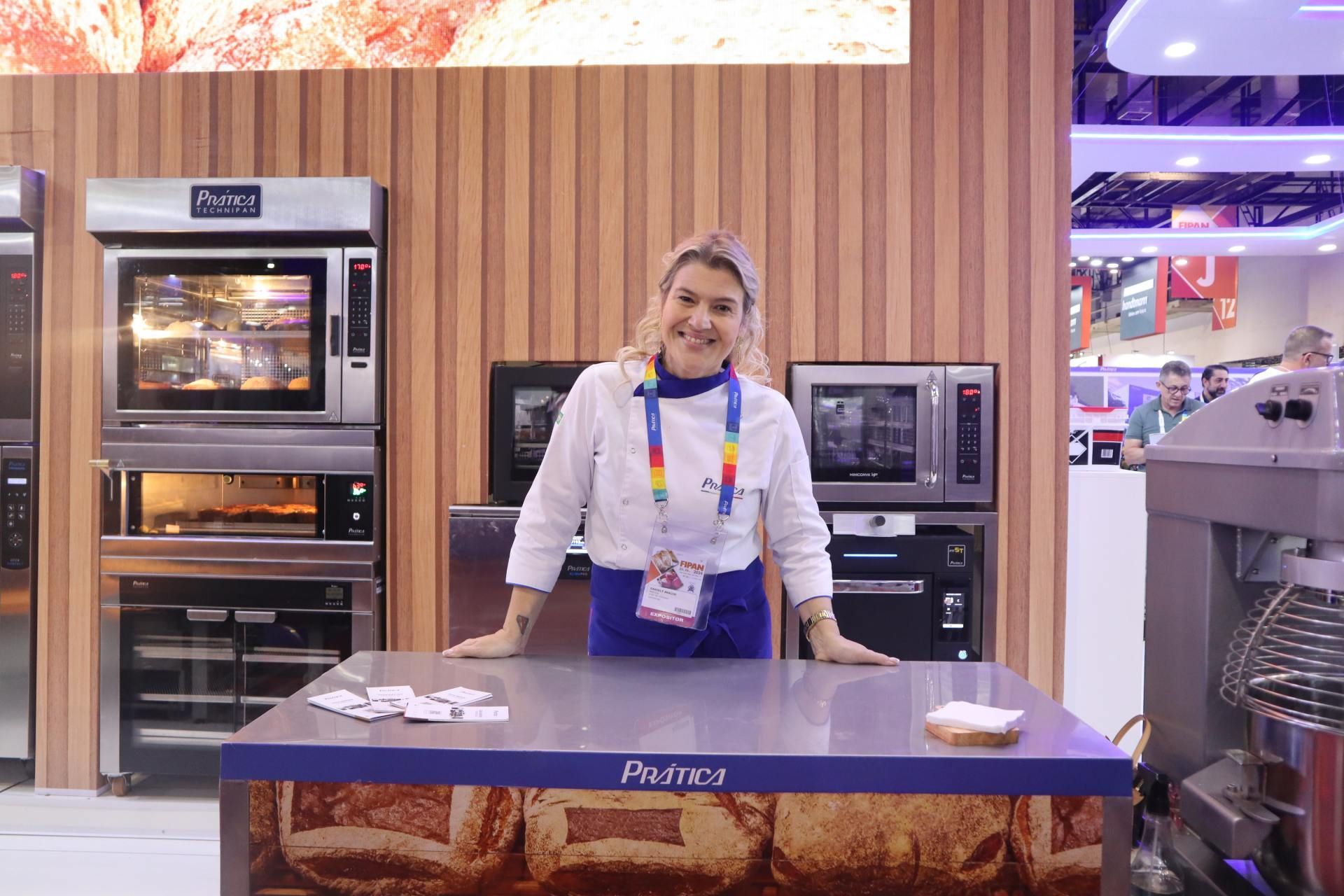 Uma mulher está parada em frente a uma mesa em uma padaria.