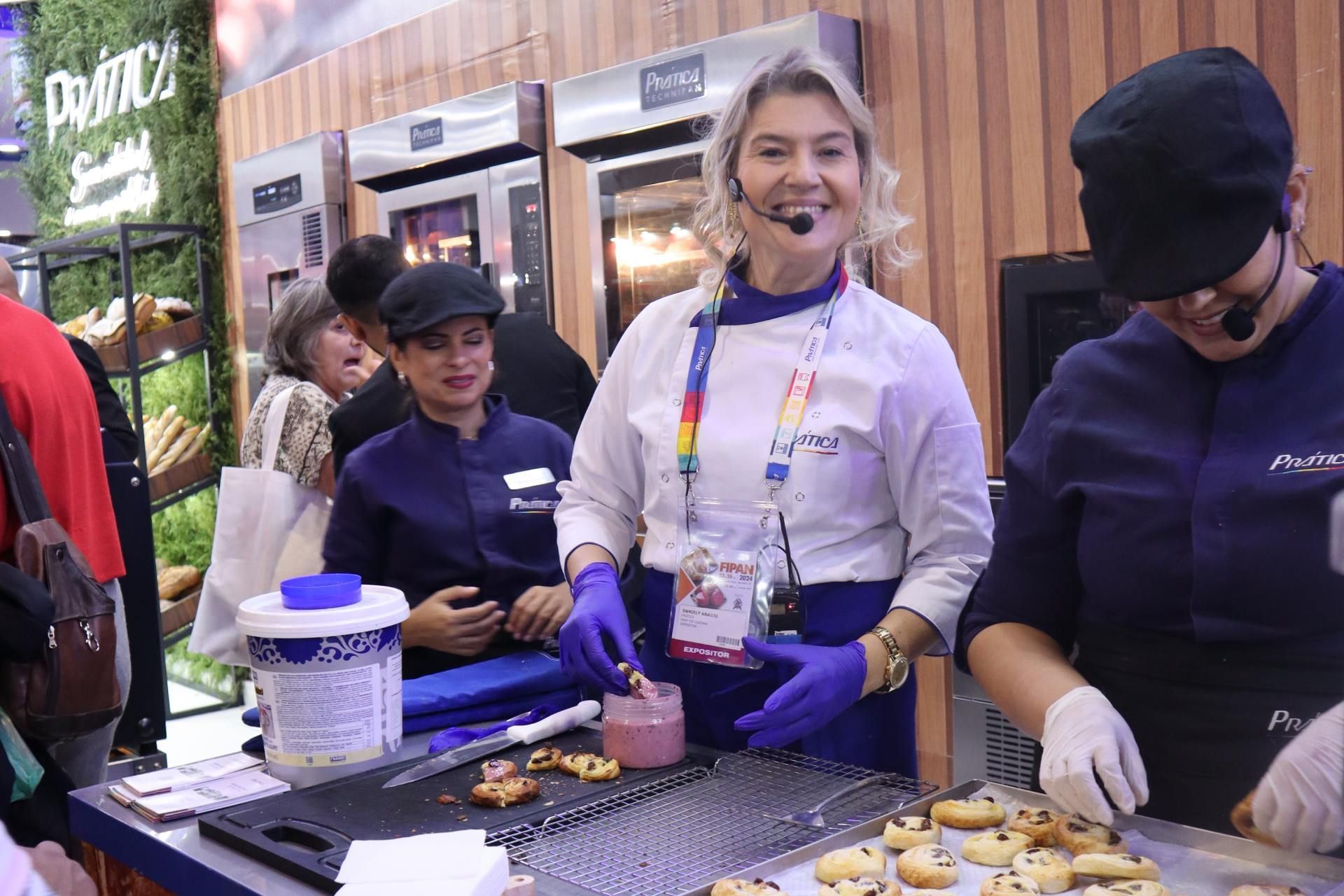 Um grupo de pessoas está em volta de uma mesa fazendo biscoitos.