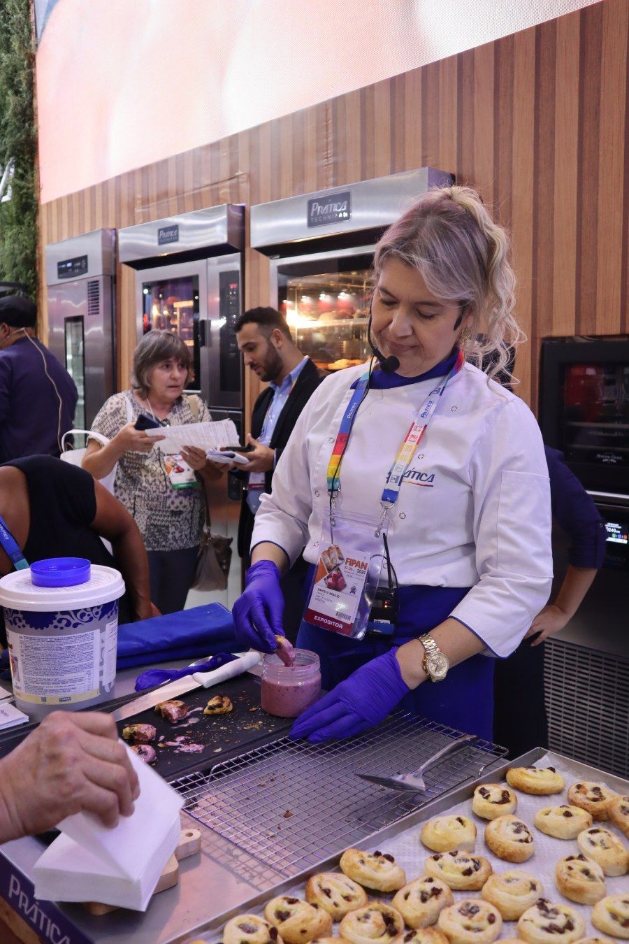 Uma mulher em uniforme de chef está preparando biscoitos em uma mesa.