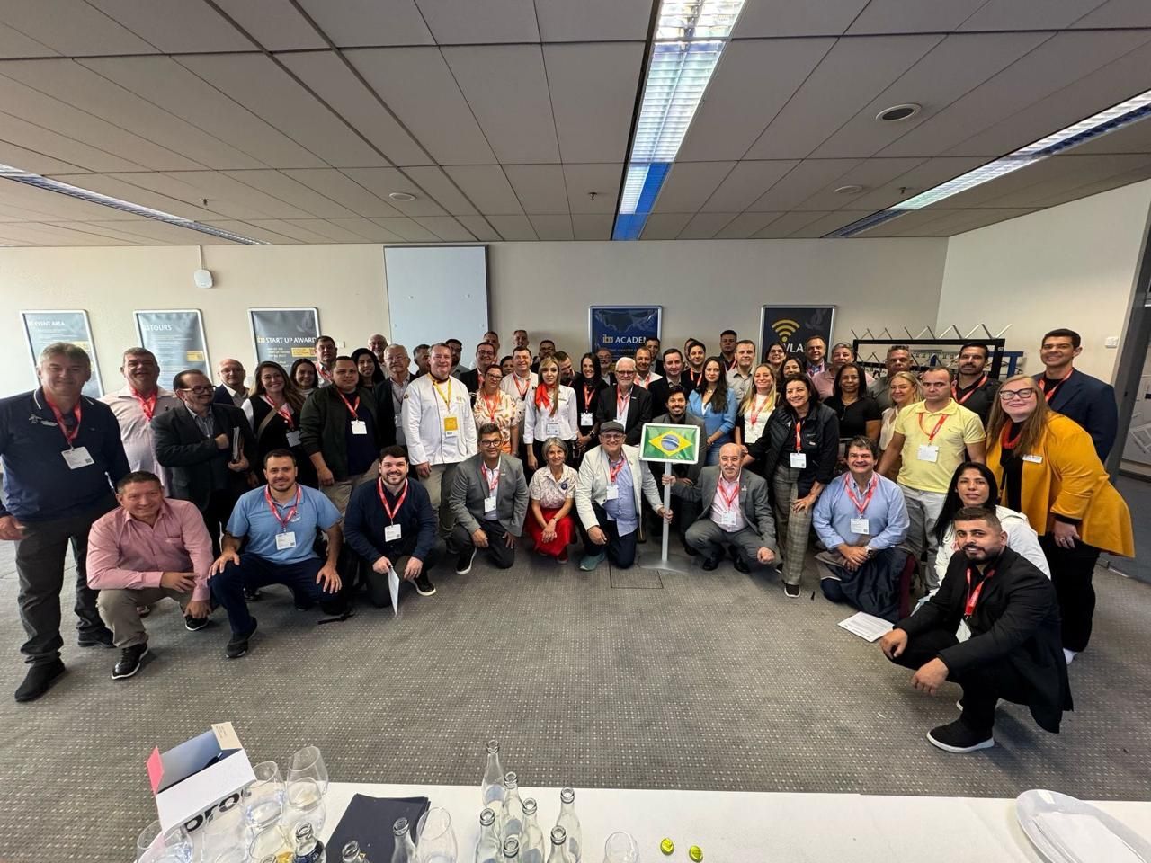 Um grande grupo de pessoas está posando para uma foto em uma sala.