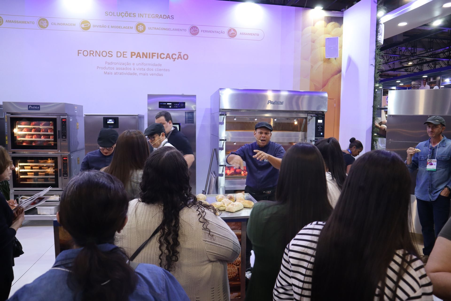 Um grupo de pessoas está em pé em frente a um forno.