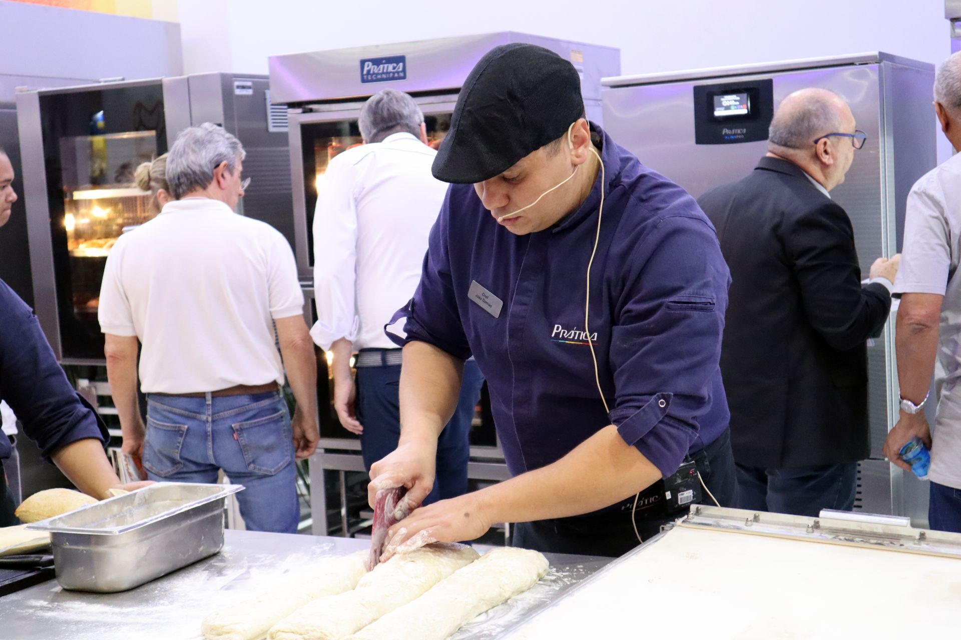 Um homem está cortando um pedaço de massa na cozinha.