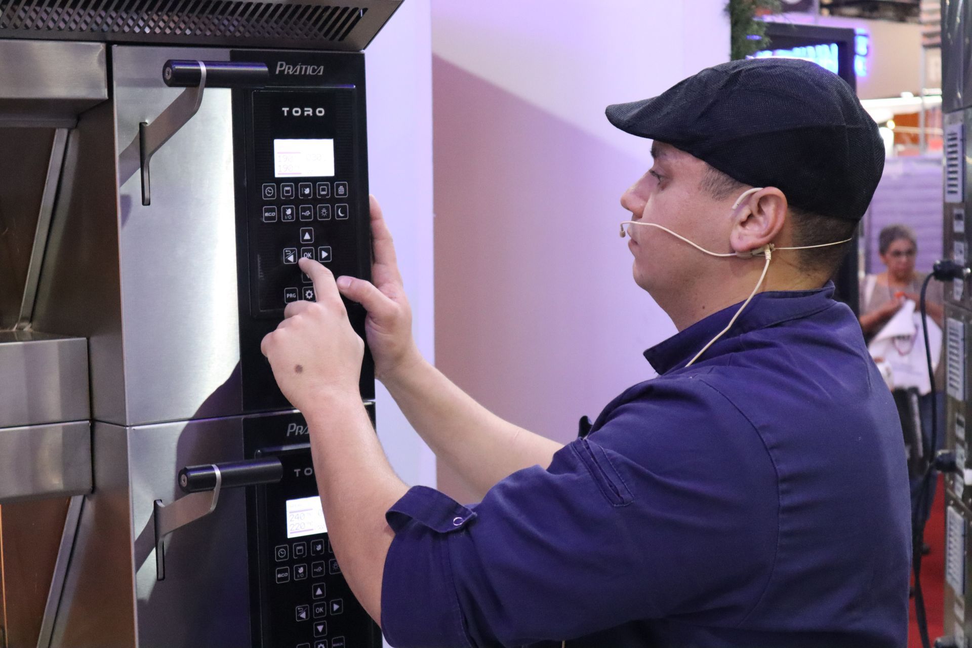 Um homem usando um chapéu e uma camisa azul está ajustando uma máquina.