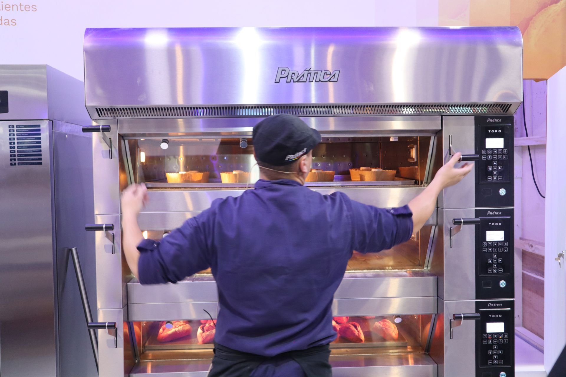 Um homem está de pé em frente a um forno com os braços estendidos.