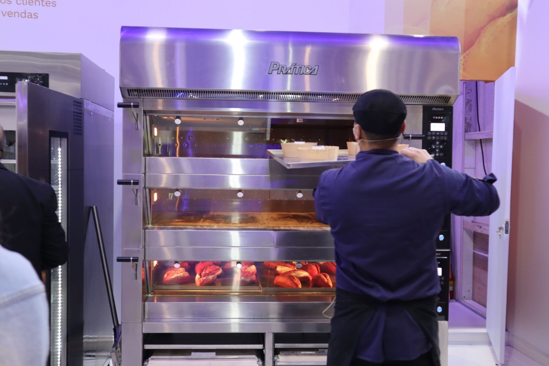 Um homem está parado em frente a um forno panera