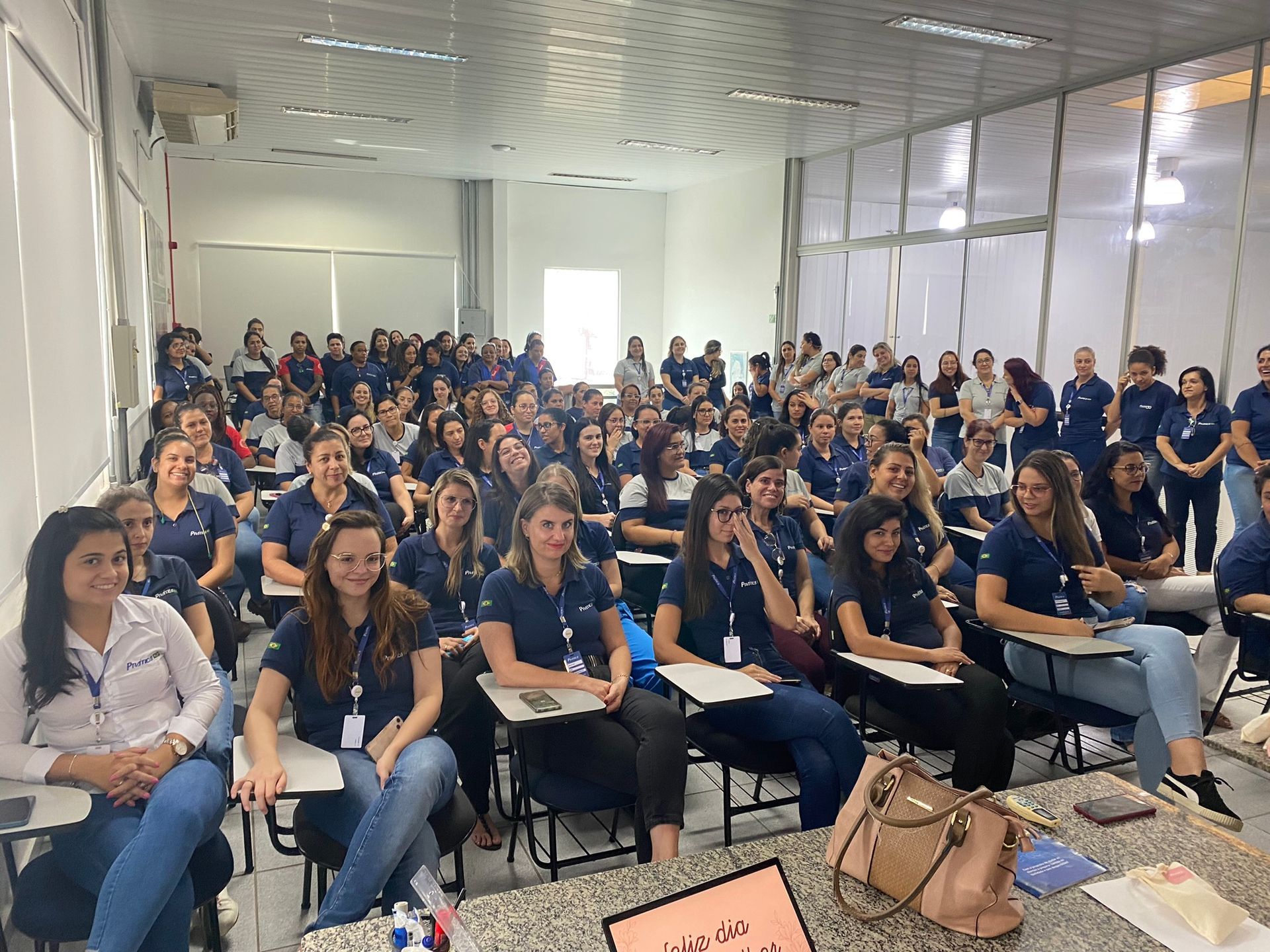 Um grande grupo de pessoas está sentado em uma sala de aula.