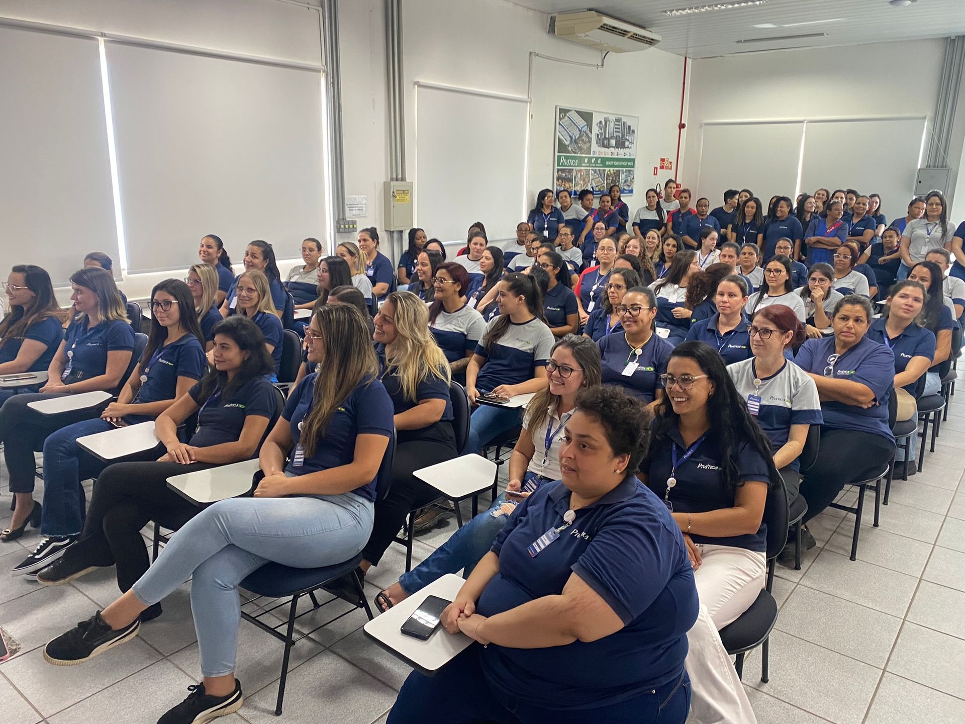 Um grande grupo de mulheres está sentado em uma sala de aula.