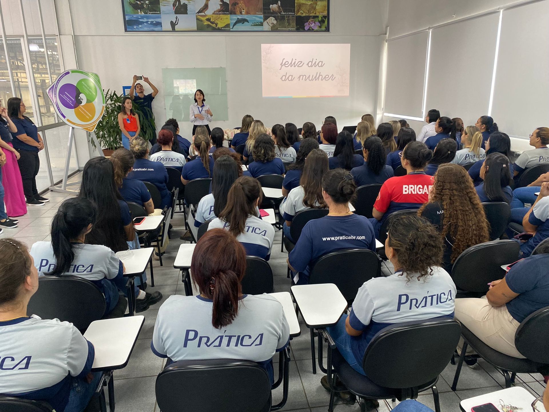 Um grande grupo de pessoas está sentado em uma sala de aula.