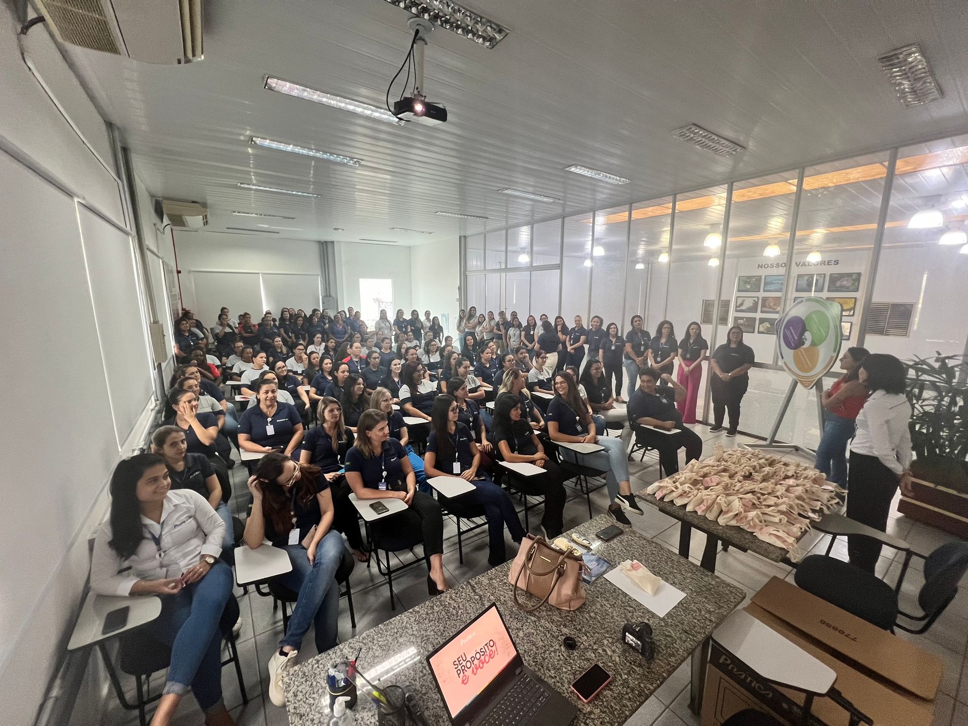 Um grande grupo de pessoas está sentado em uma sala de aula.