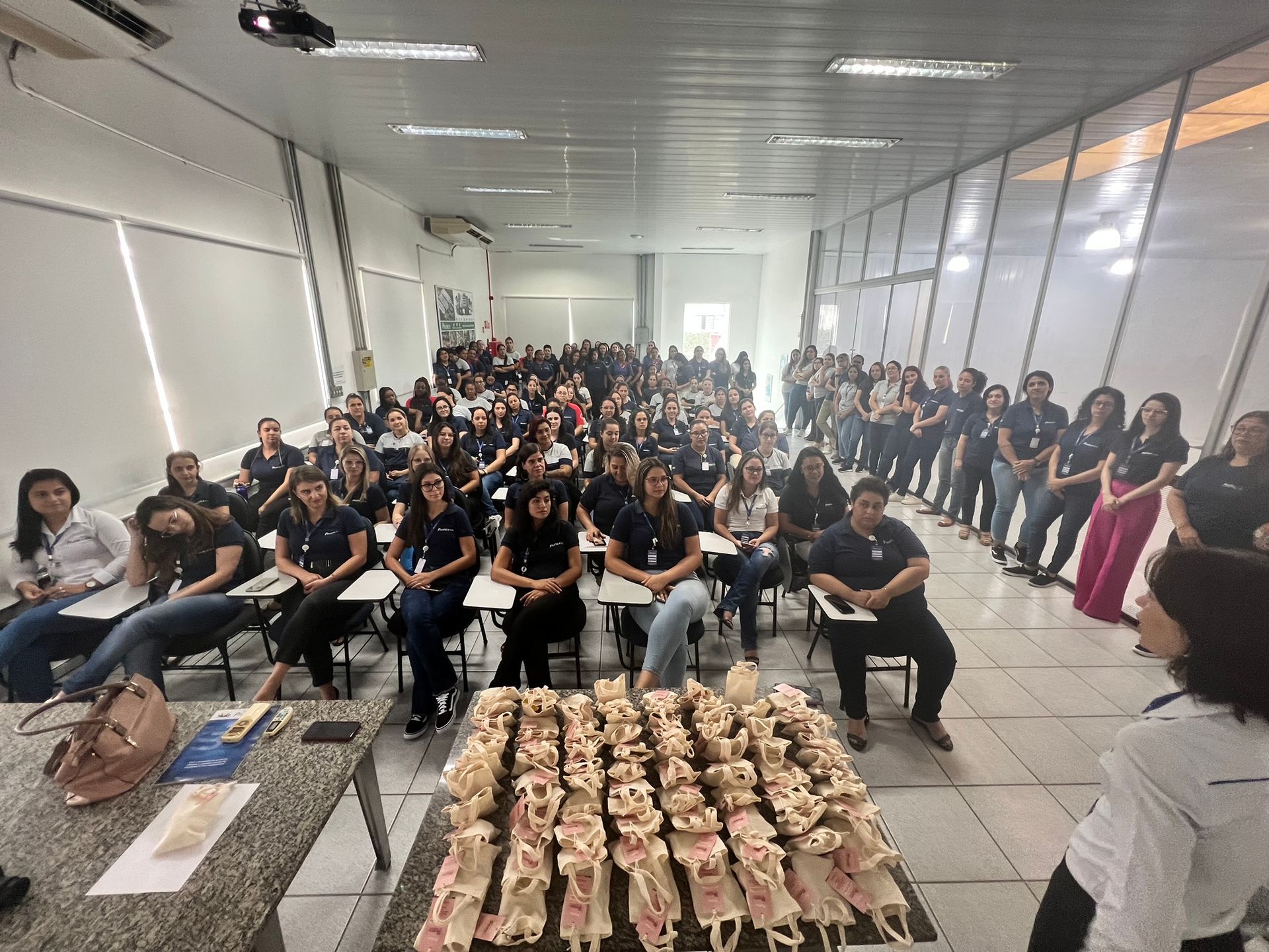 Um grande grupo de pessoas está sentado em uma sala de aula.