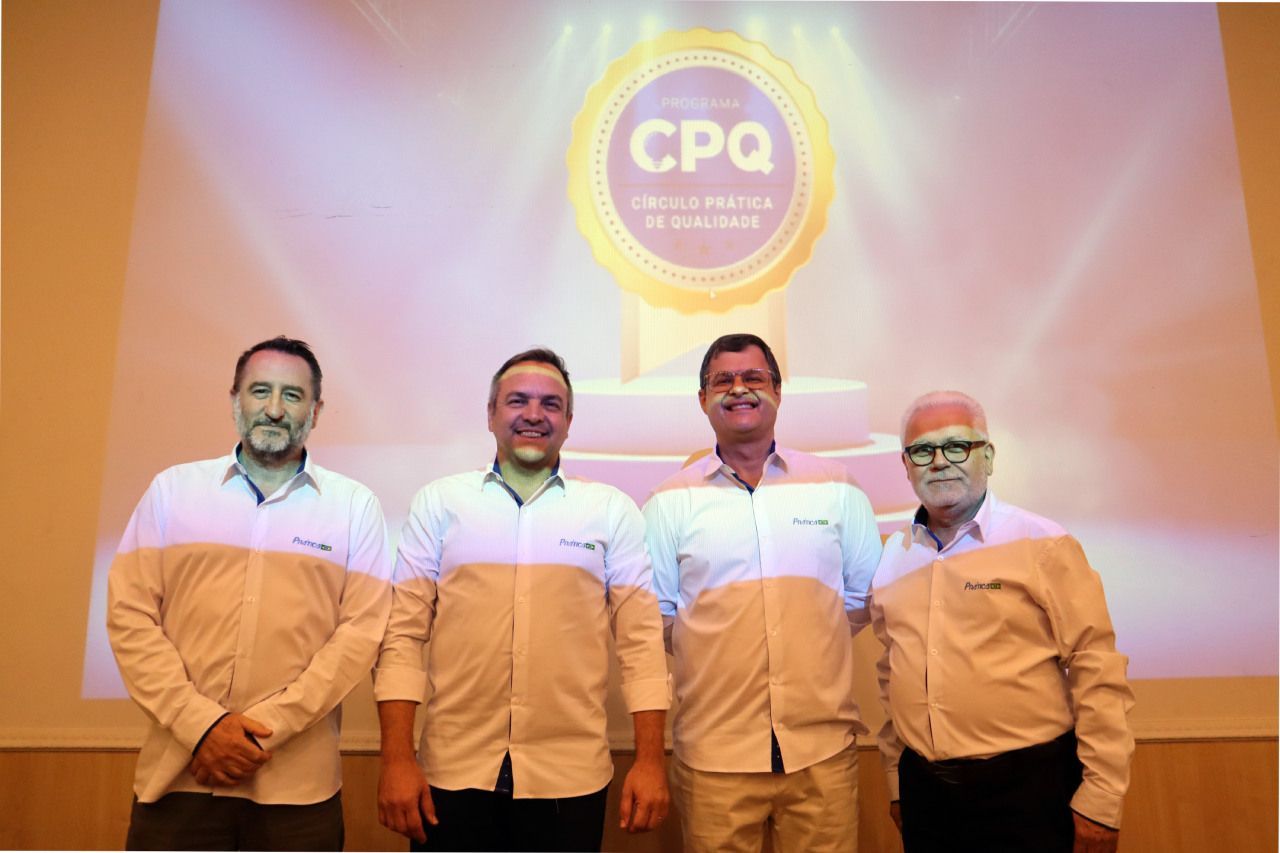 Um grupo de homens está posando para uma foto em frente a uma tela grande.
