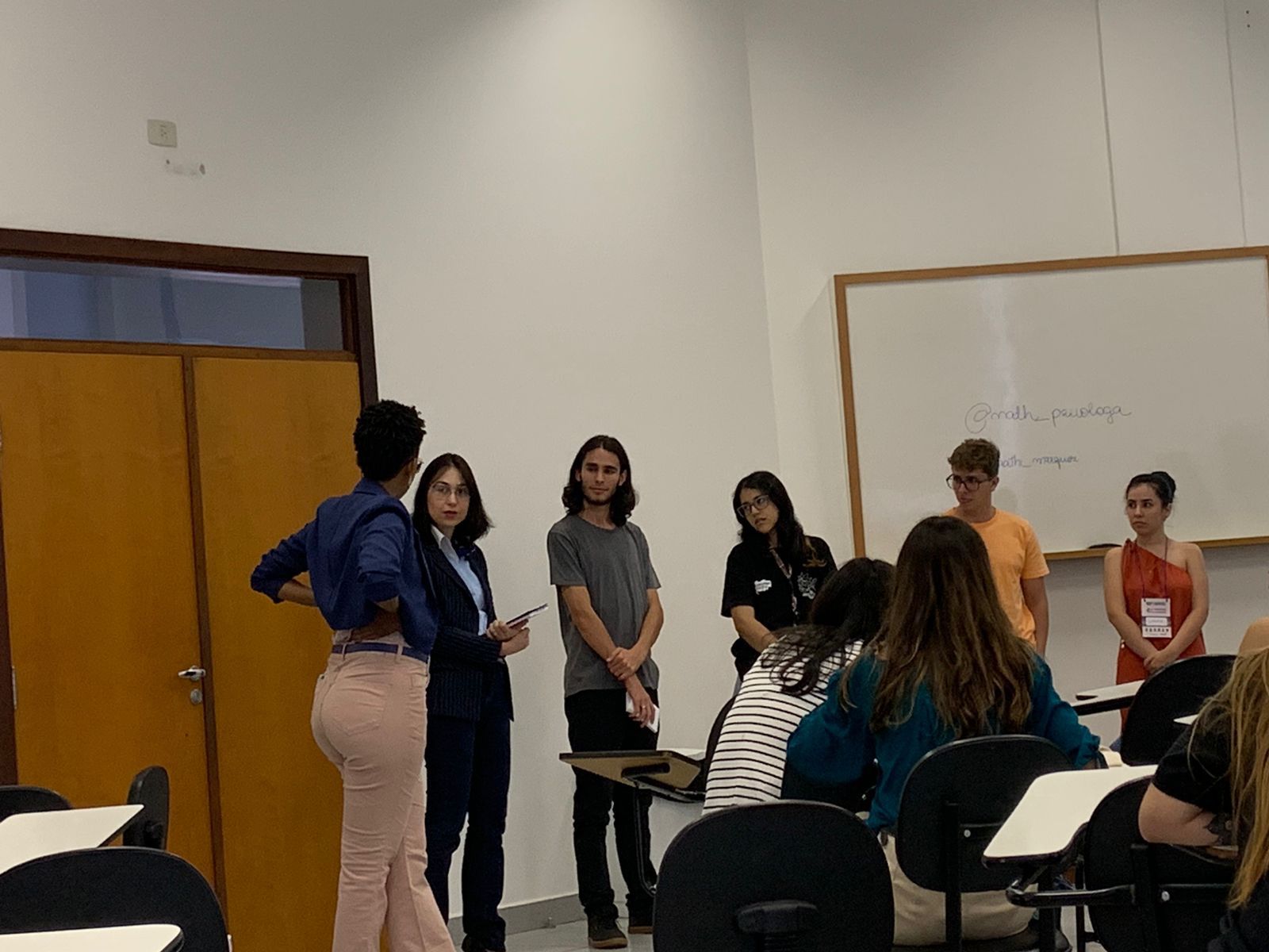 Um grupo de pessoas está em uma sala de aula conversando entre si.