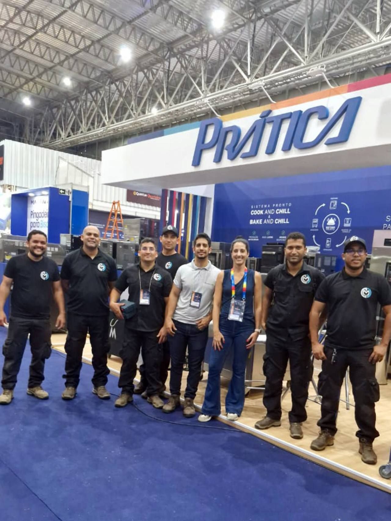 Um grupo de pessoas está posando para uma foto em frente a uma placa de prática.