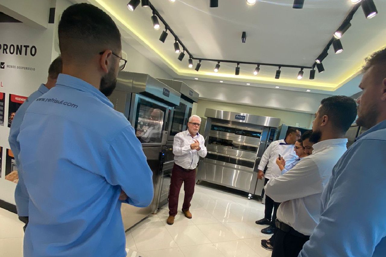 Um grupo de homens está em uma sala com um homem parado na frente deles.