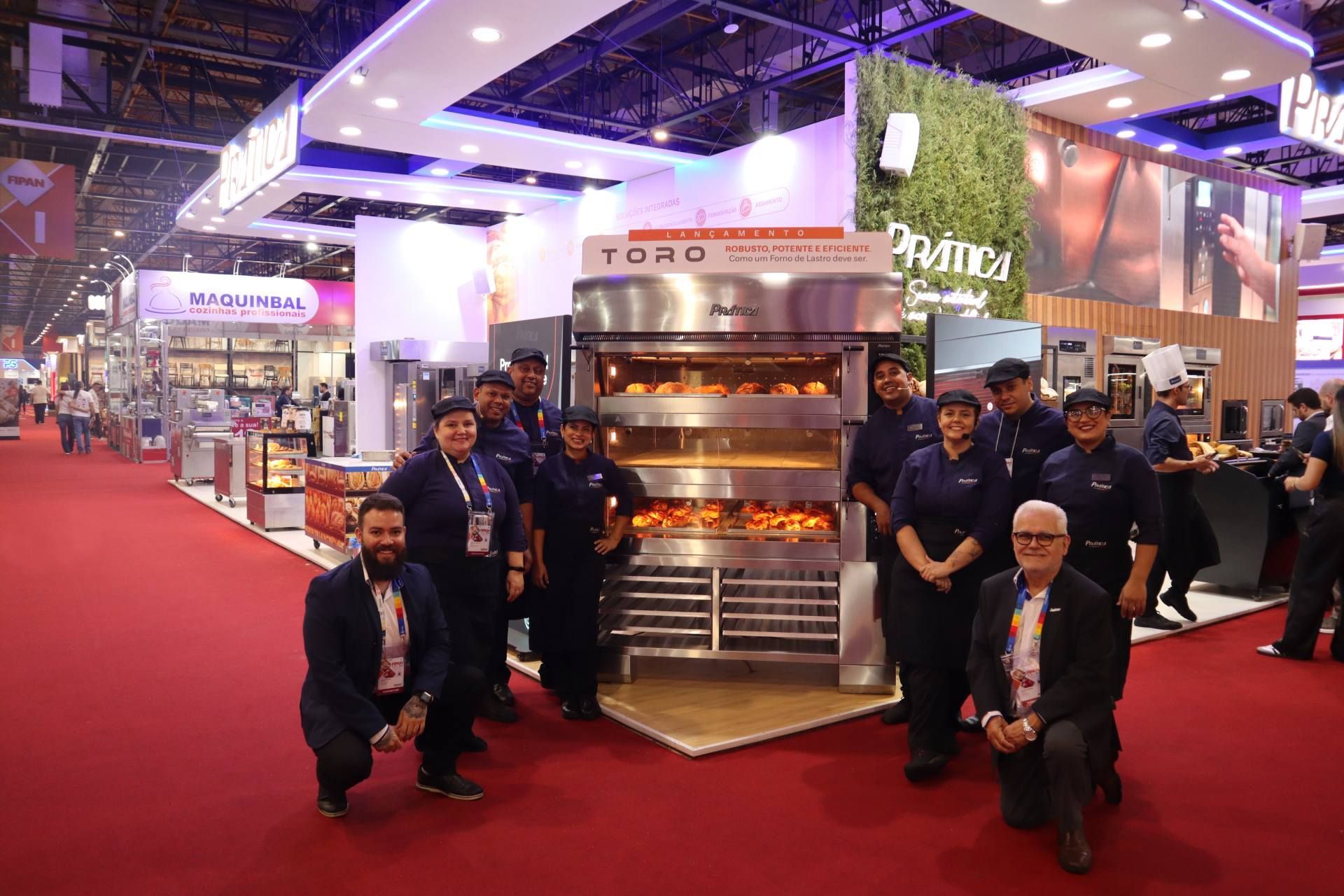 Um grupo de pessoas está posando para uma foto em frente a um forno.