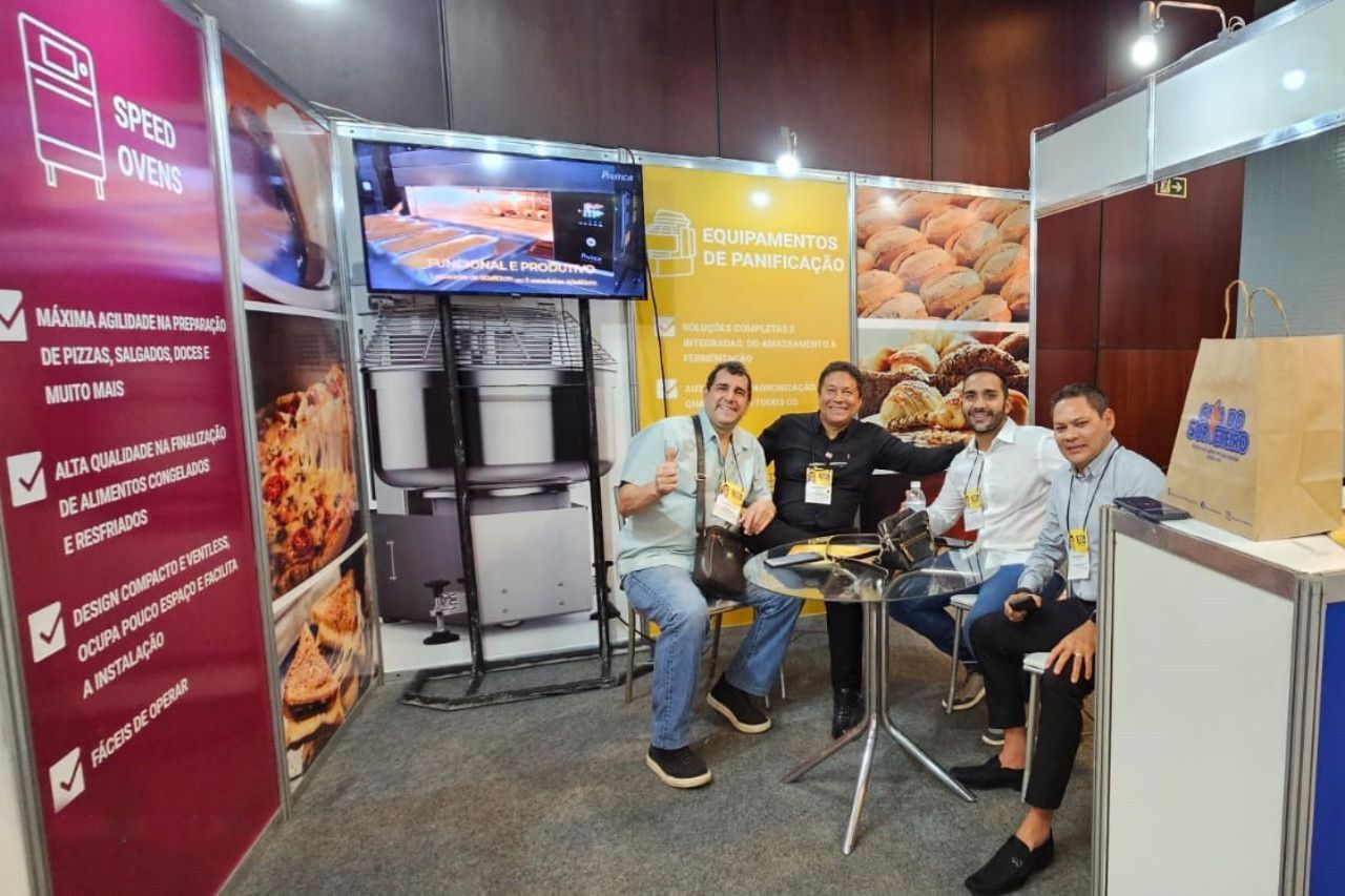 Um grupo de homens está sentado em uma mesa em frente a uma cabine.