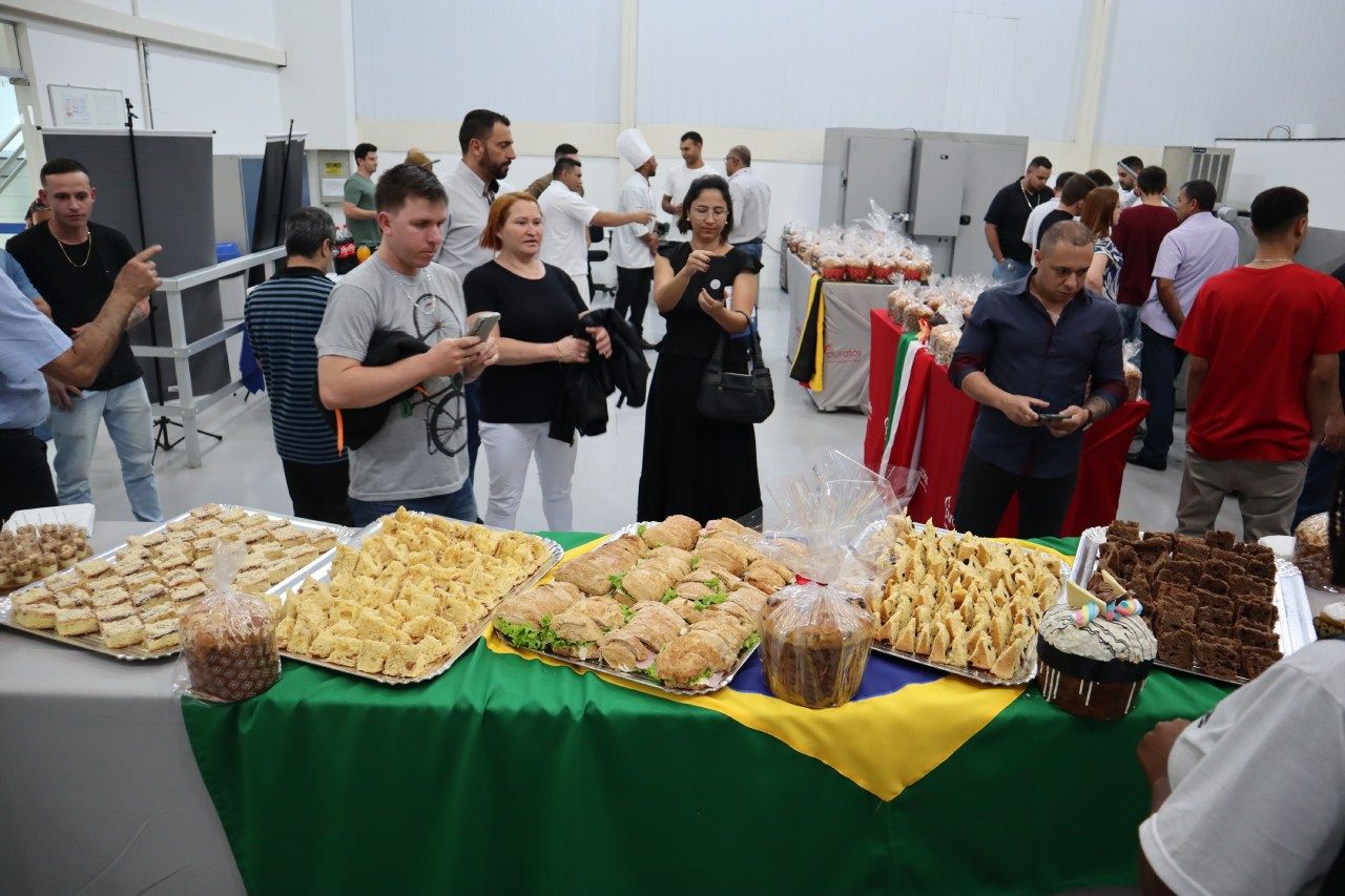 Um grupo de pessoas está em pé ao redor de uma mesa com comida.