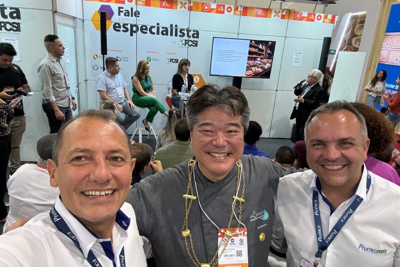 Três homens estão posando para uma foto em uma convenção.