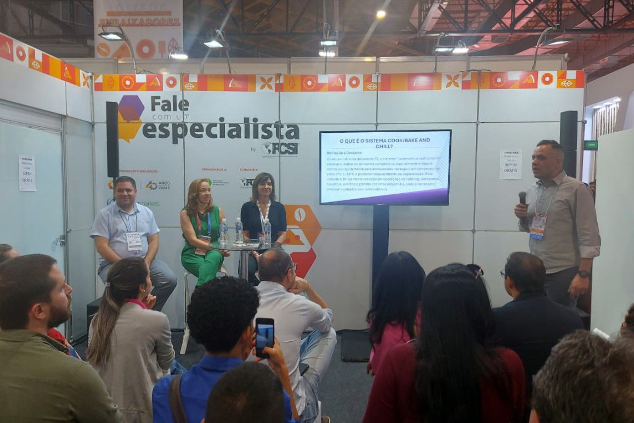 Um grupo de pessoas está sentado em frente a uma placa que diz fale especialista