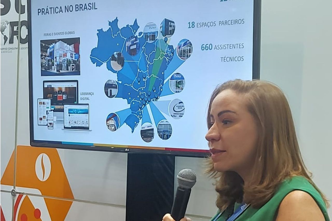 Uma mulher segura um microfone em frente a uma tela grande.